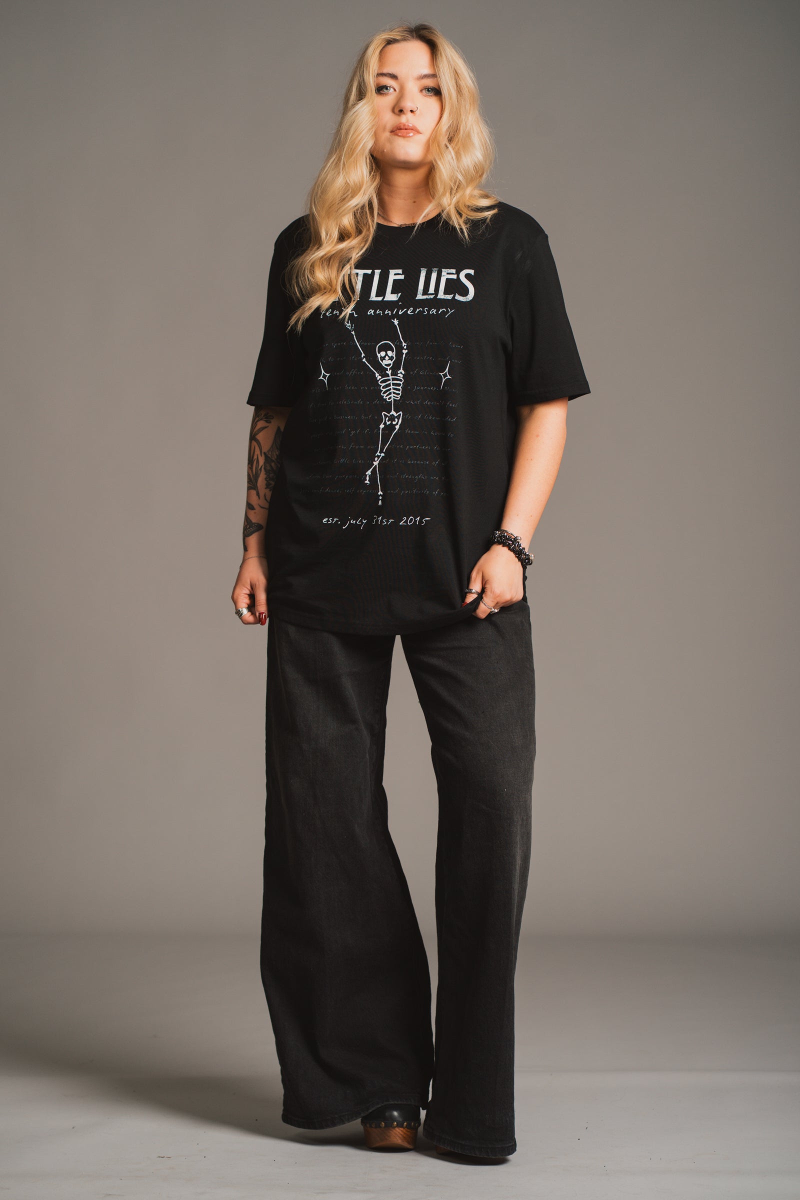 Model wearing Little Lies 10th Anniversary Graphic black t-shirt with vintage Little Lies design.