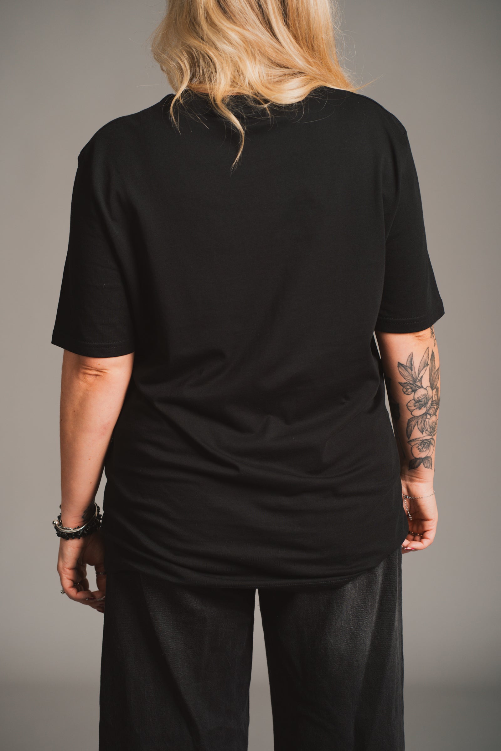 Model wearing Little Lies 10th Anniversary Graphic black t-shirt with vintage Little Lies design.