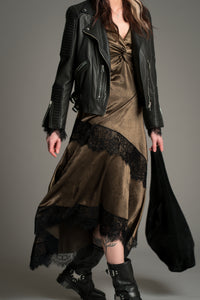 Little Lies Arabella Satin Maxi Dress in olive satin with black lace panels, styled with a black leather biker jacket, chunky boots, and a black Olsen bag.