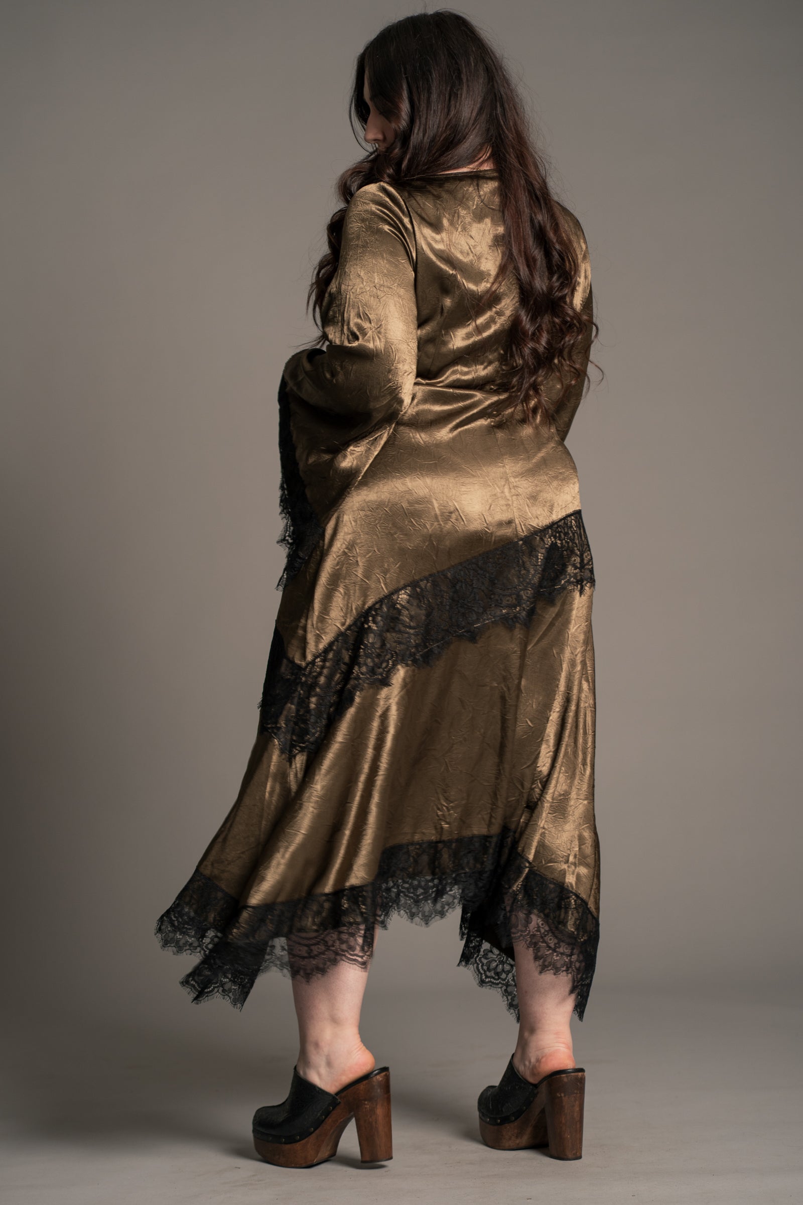 Full length view of Little Lies Arabella Satin Maxi Dress in olive satin styled with boots