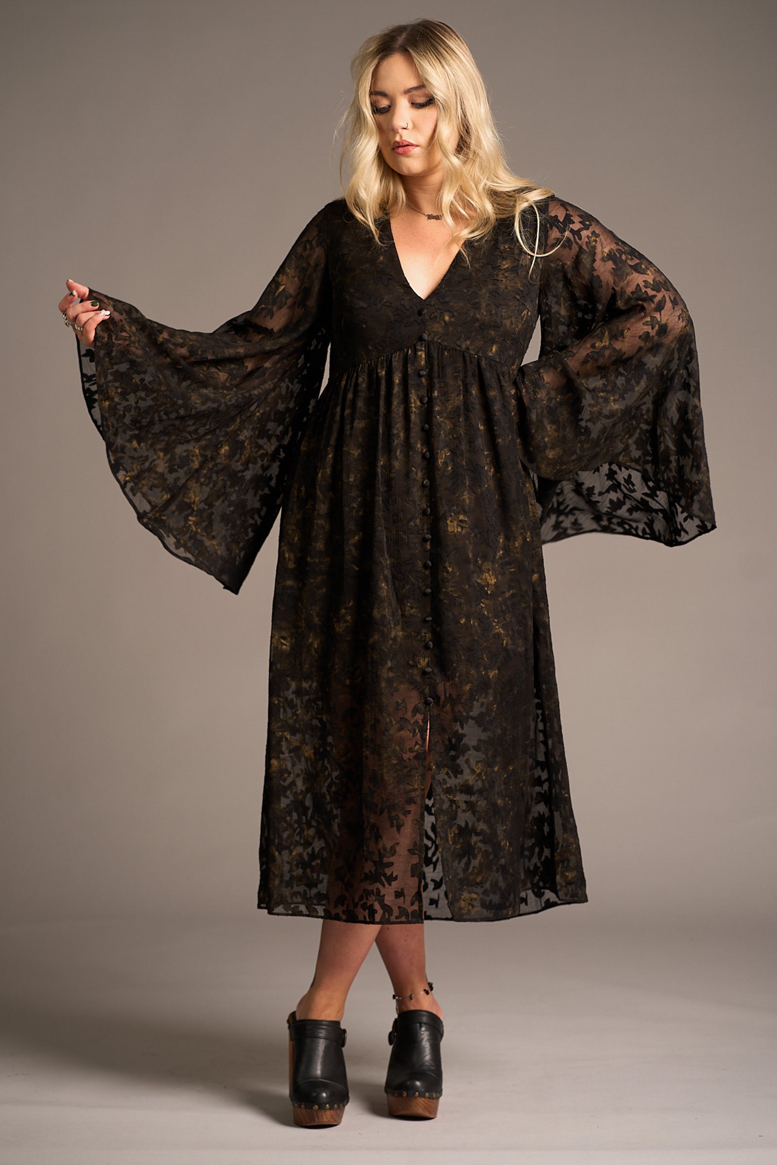 Erin wears the Bella Donna Midi Dress featuring sheer black floral overlay and bell sleeves against a neutral backdrop, Stevie Nicks inspired styling studio