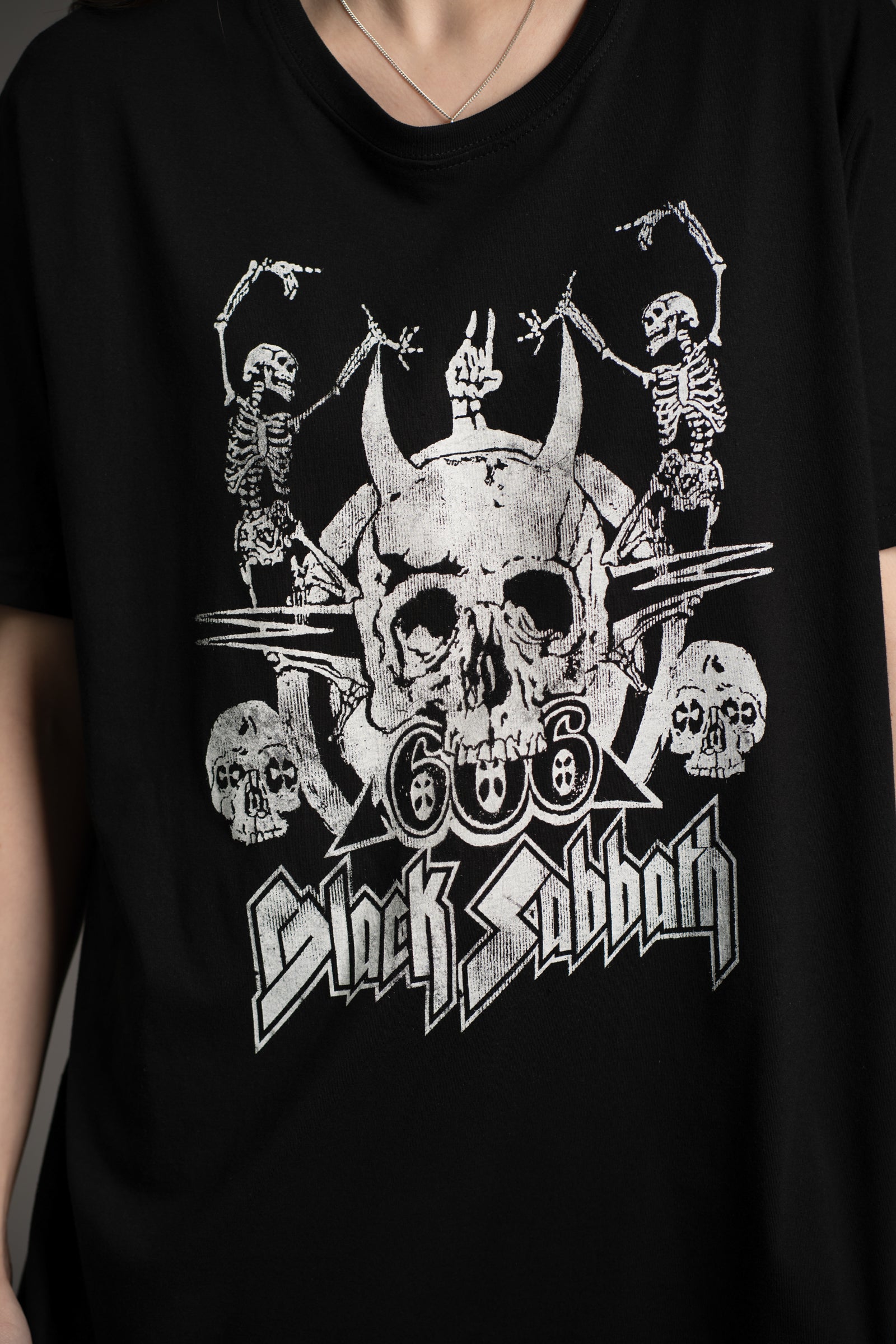 Close-up of Black Sabbath Dancing Band tee graphic featuring skull, skeletons, and 666 design from Little Lies collection