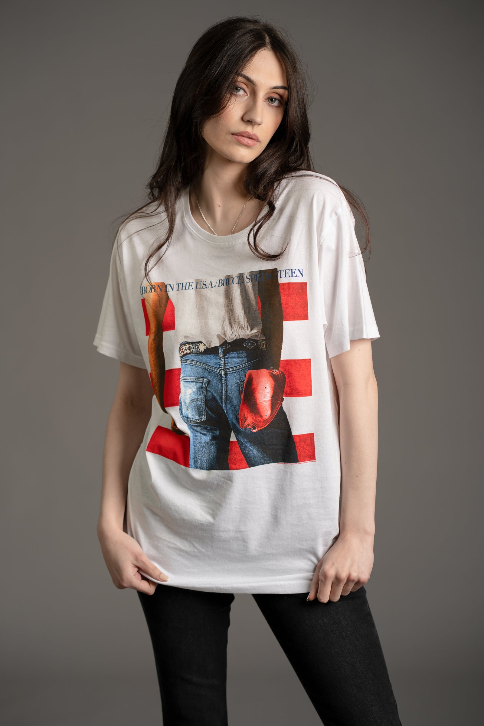 Front view of model Andie wearing the Bruce Springsteen Born in the USA graphic band tee in white featuring iconic album cover design from Little Lies collection