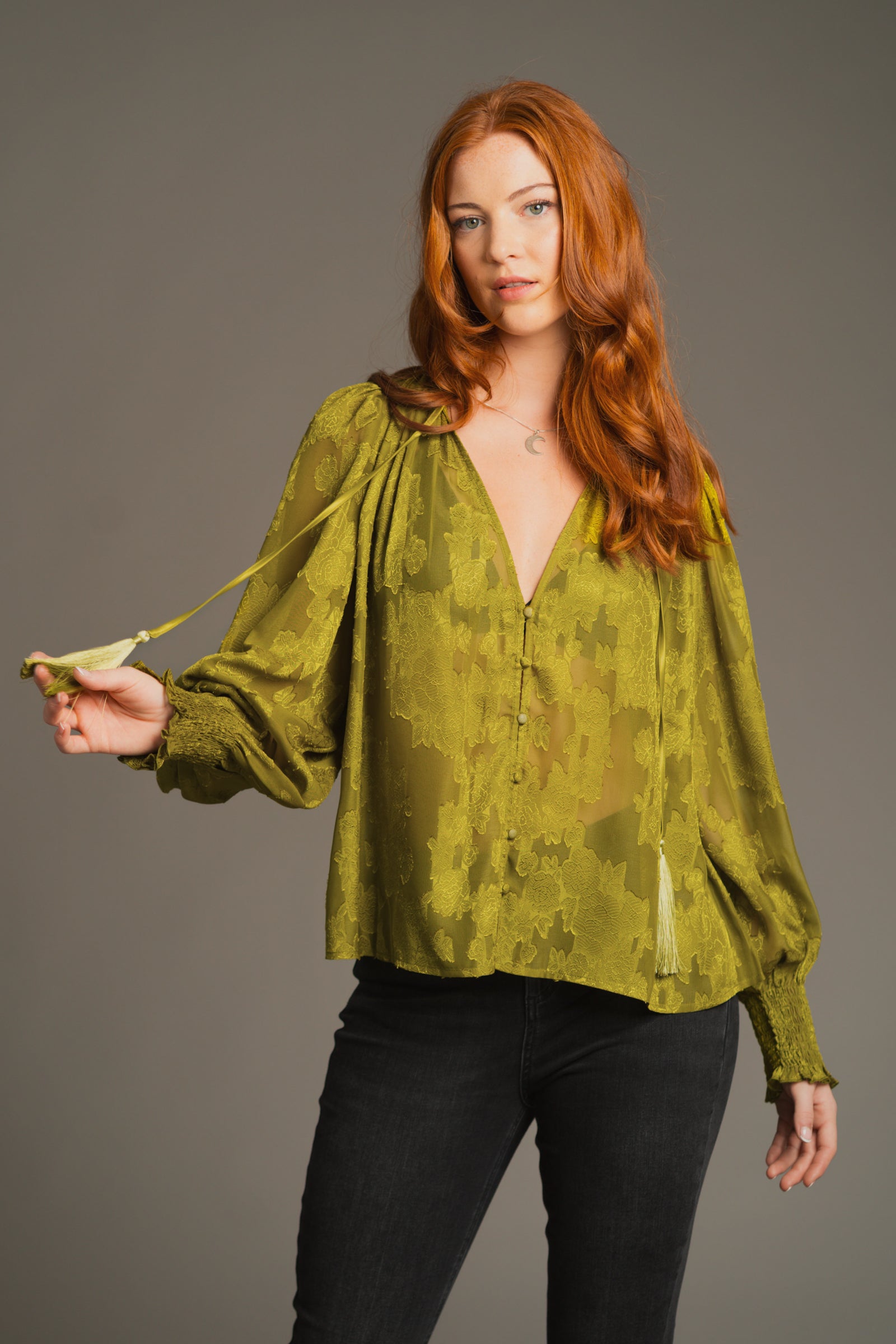 Anna wearing a Olive Cassia Smock top with button front and long sleeves against a gray background