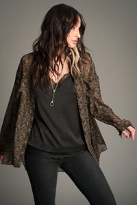 Victoria wears Little Lies Cinnamon Girl Paisley Chiffon Shirt styled open over a black satin cami, showing the lightweight sheer paisley fabric and relaxed flowing fit.