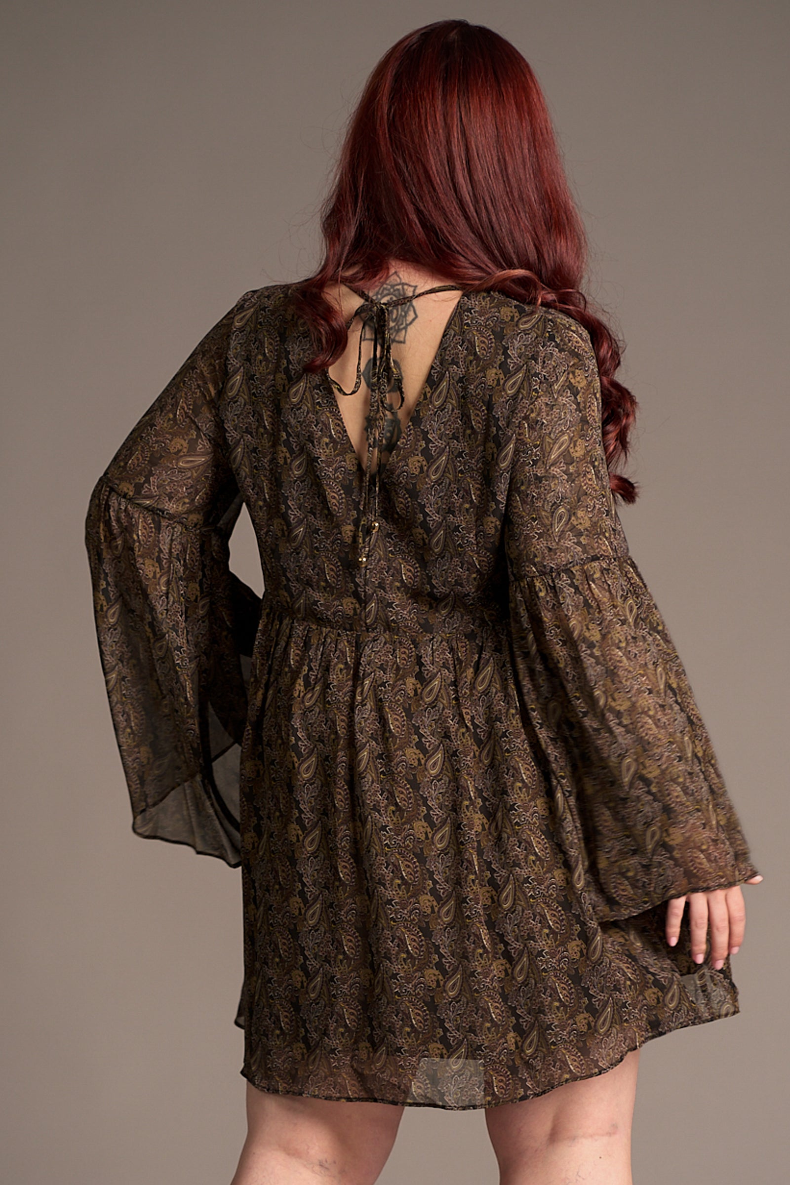 Taylor shows the back of the Cinnamon Girl Paisley Chiffon Smock Dress, fabric and tie back detail shot showing autumnal style.