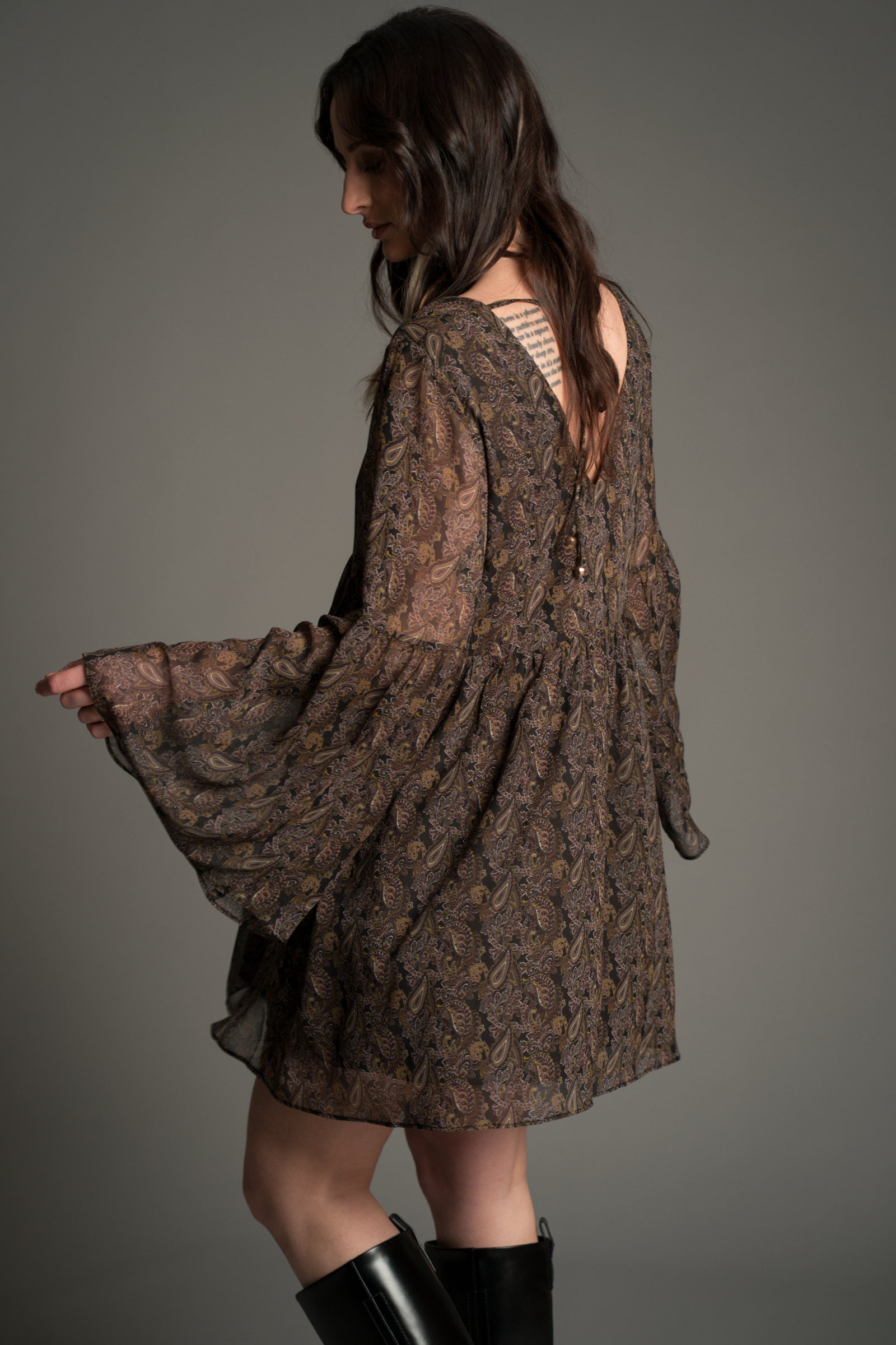 Little Lies Cinnamon Girl Paisley Chiffon Smock Dress shown from the back, featuring sheer lightweight paisley fabric, flared sleeves, and a relaxed flowing silhouette.