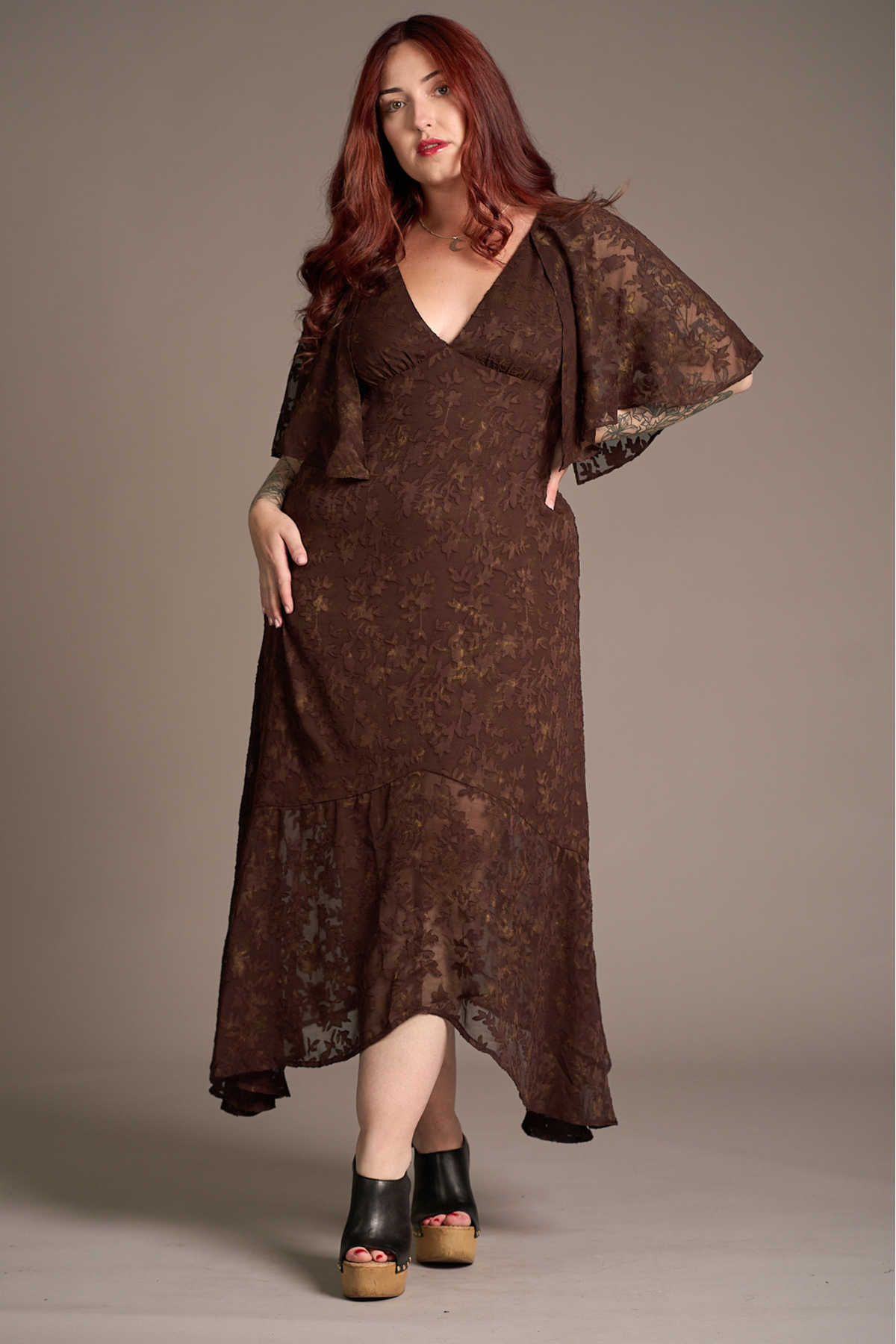 Taylor wearing the Little Lies Brown Sugar Chiffon Midi Dress with flutter sleeves and a flowing asymmetrical hemline, studio setting