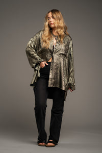 Erin wears Little Lies Luna Metallic Shirt in gold, styled oversized with textured metallic finish, dark trousers and sandals.