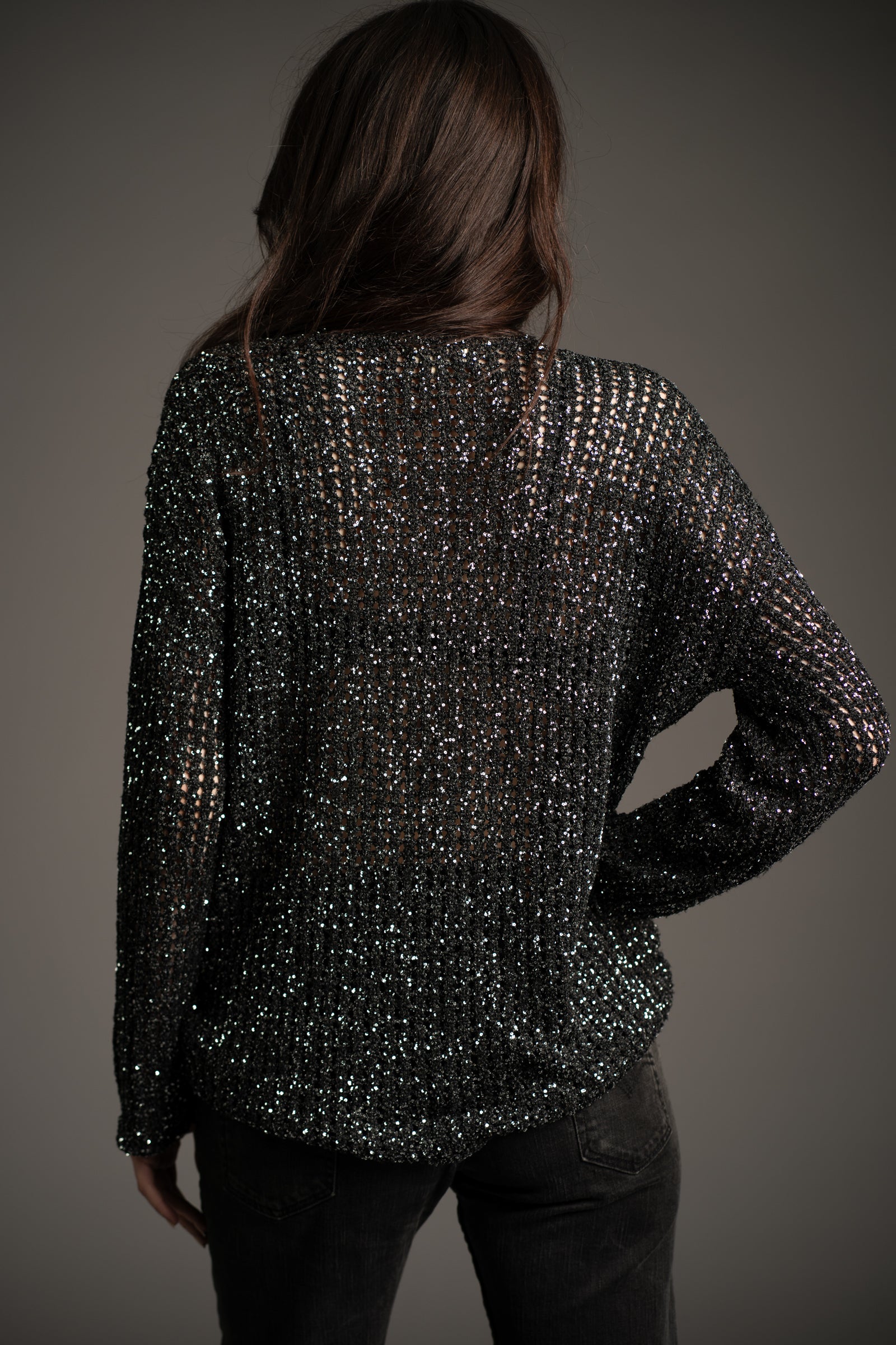 Little Lies Dazed & Confused sequin knit, back view showing shimmering sequin detail, styled with dark jeans in studio setting