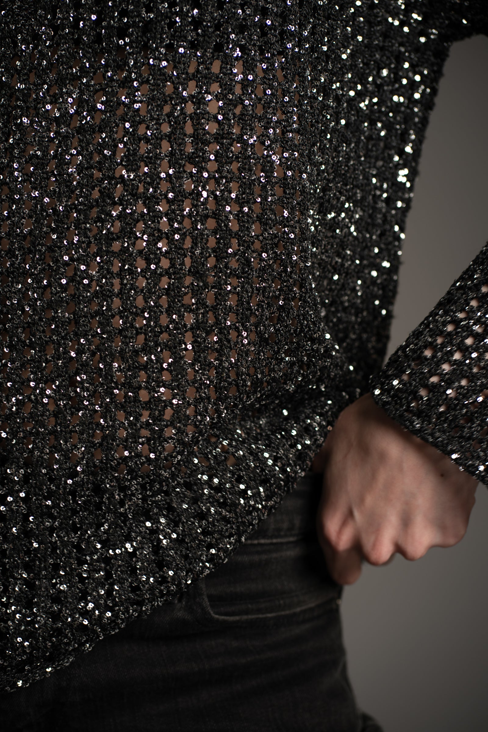 Little Lies Dazed & Confused sequin knit sweater in black, close-up showing intricate open-knit texture with shimmering sequins and cuff detail