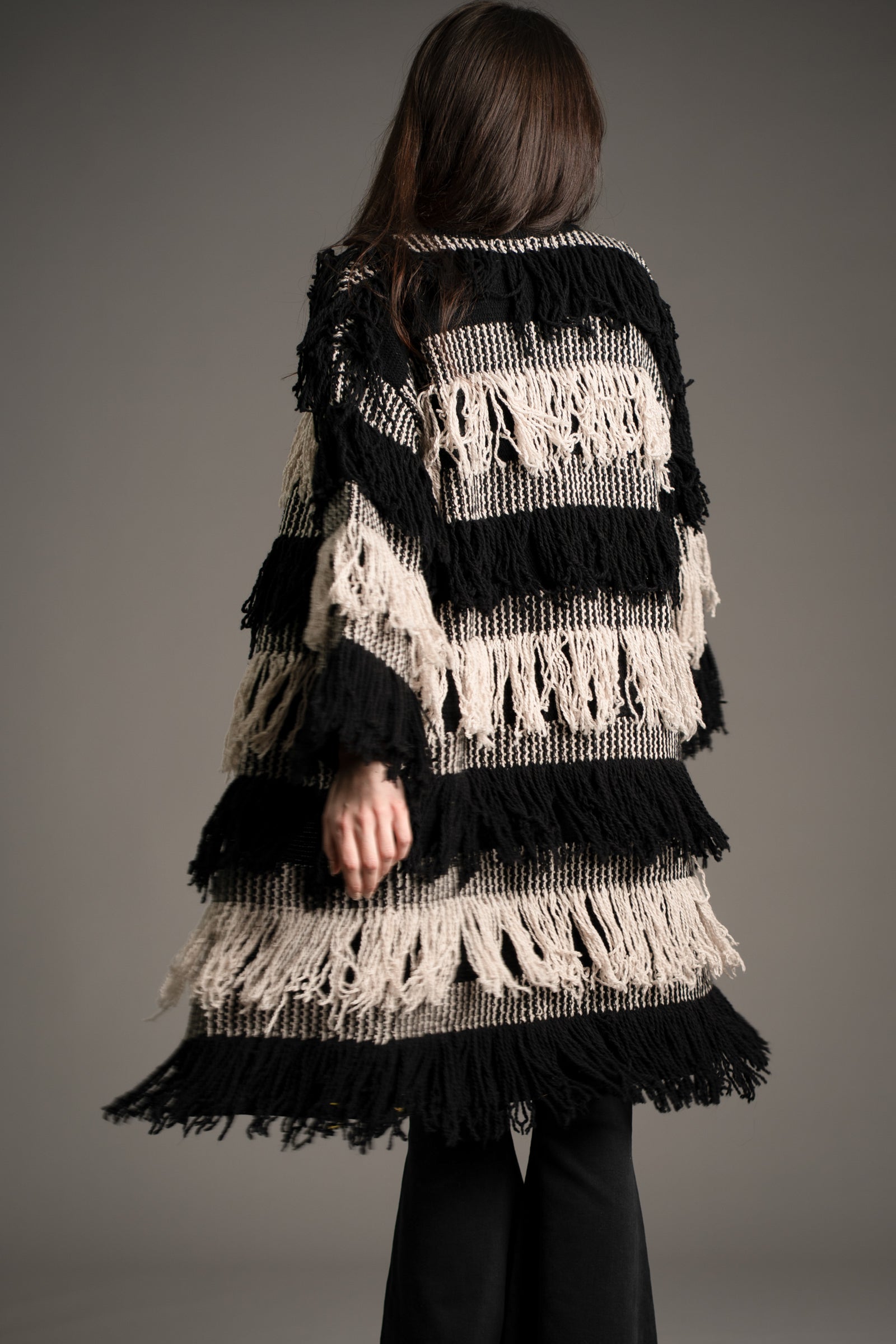Back view of Little Lies Desperado Shaggy Cardigan with black and cream layered fringe detailing, studio setting