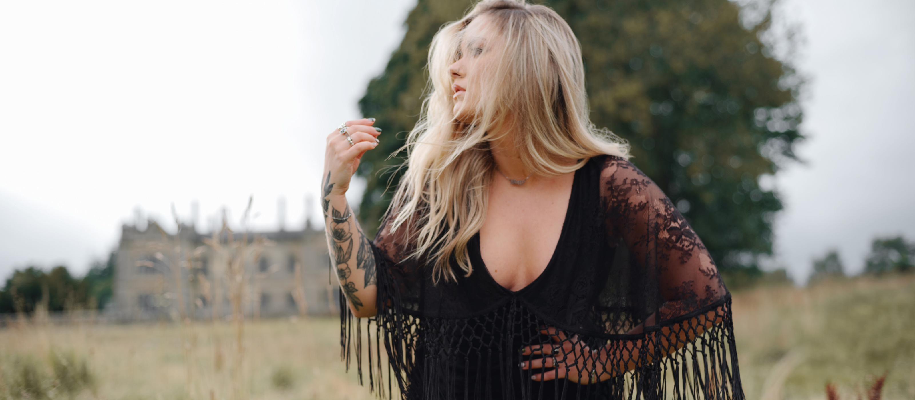 Erin wears Tango in the Night Lace Midi Dress, Stevie Nicks inspired styling, outdoor, set against a vintage manor and wild grass.