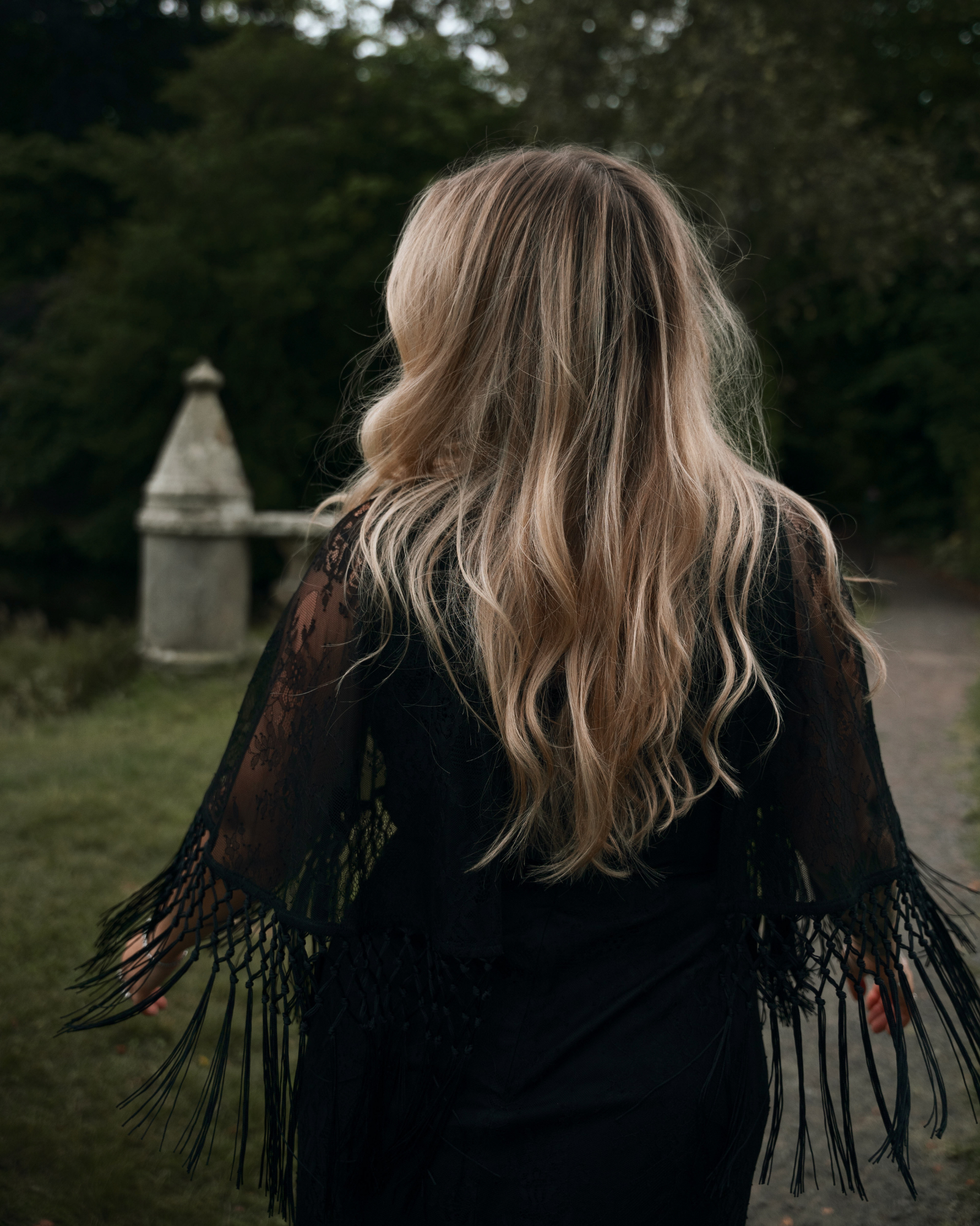 Erin showing the back of the Tango in the Night Lace Midi Dress, Stevie Nicks inspired styling, outdoor, set against stone ruins and woodland