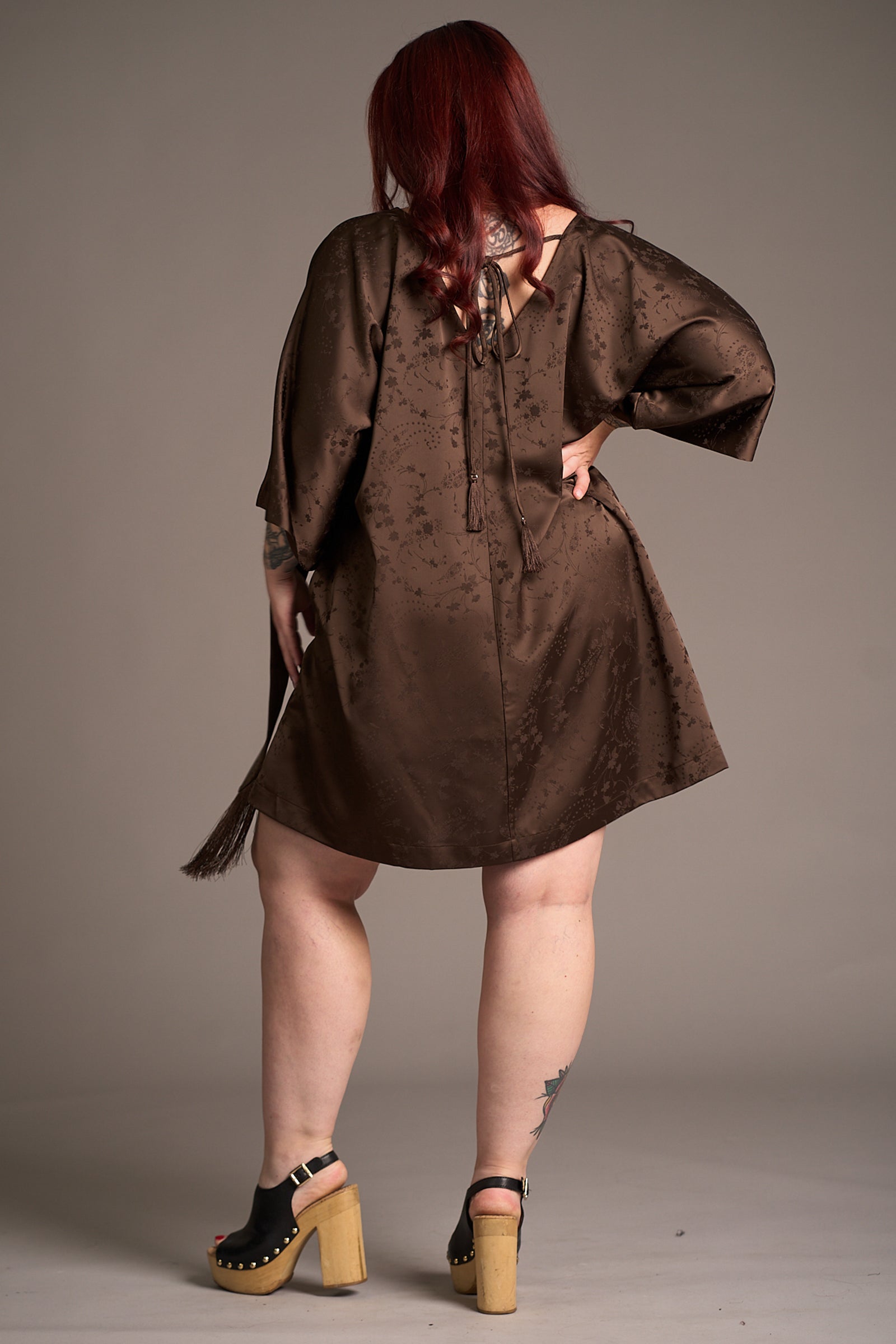 Taylor shows the back of the Evermore Espresso Batwing Mini Dress, fabric and tie back detail shot showing autumnal style.