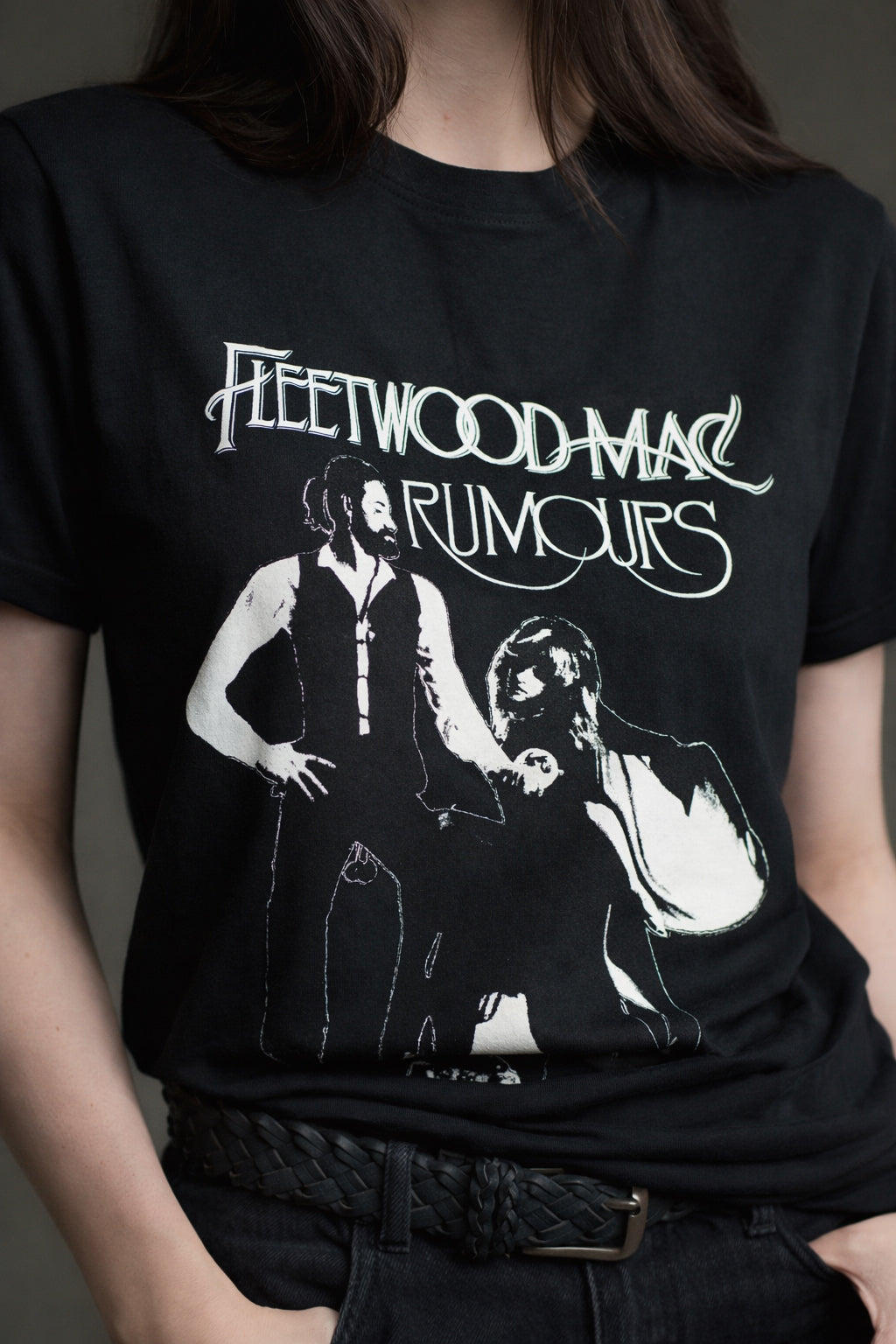 Black Fleetwood Mac Rumours band tee featuring the iconic album artwork, styled with black jeans and a braided belt.
