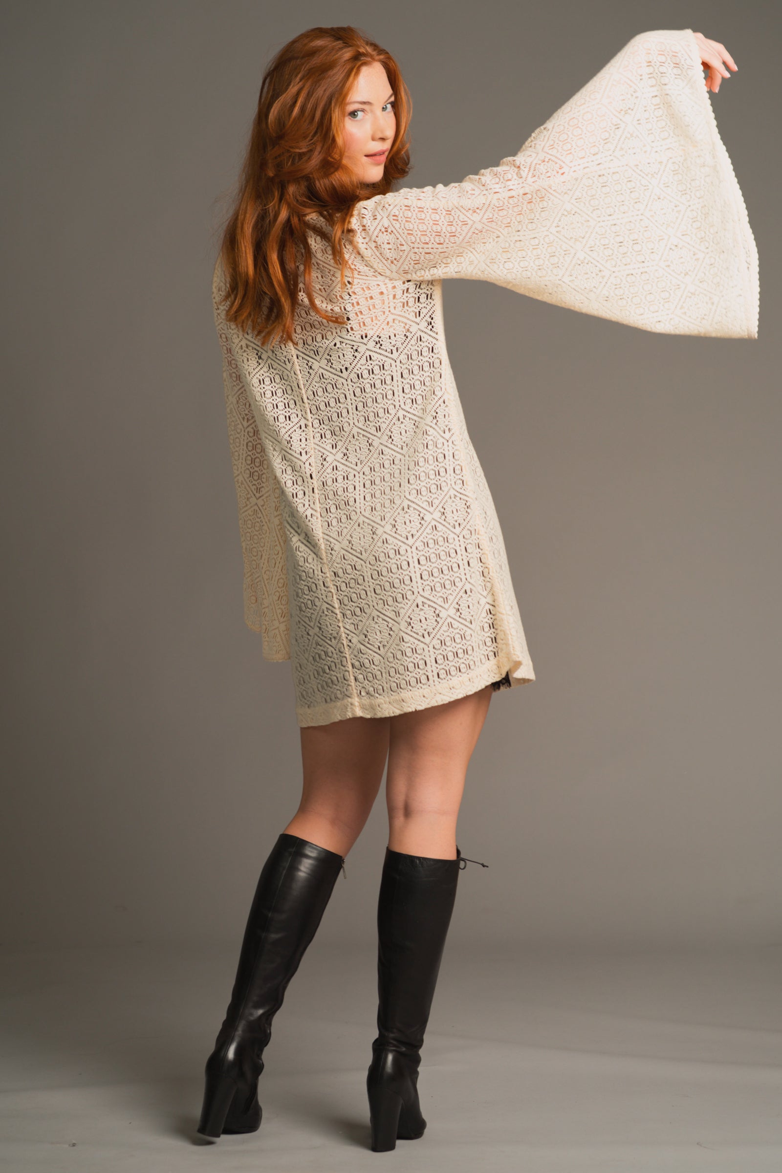 Anna showing the back of the Goldie Crochet Mini Dress, with dramatic flared sleeve detail and effortless boho styling