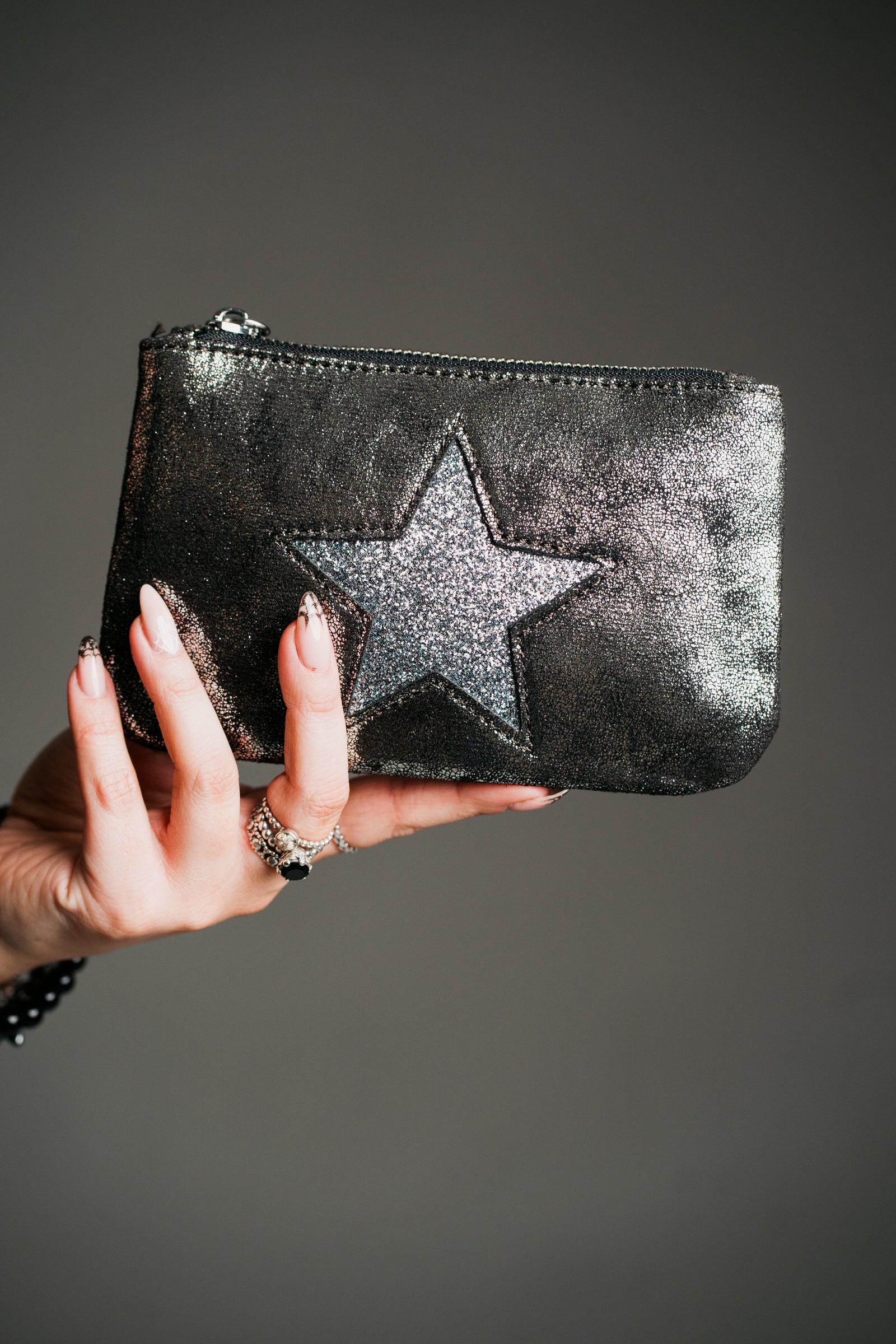 Close-up product shot, statement purse in metallic finish with star motif and zip closure.