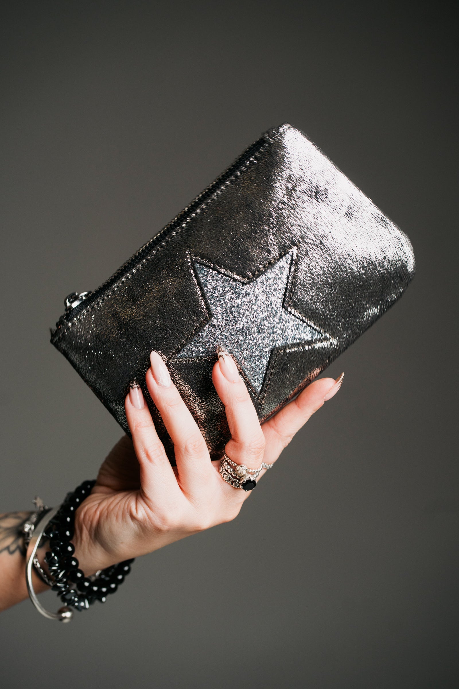 Close-up product shot, statement purse in metallic finish with star motif and zip closure.