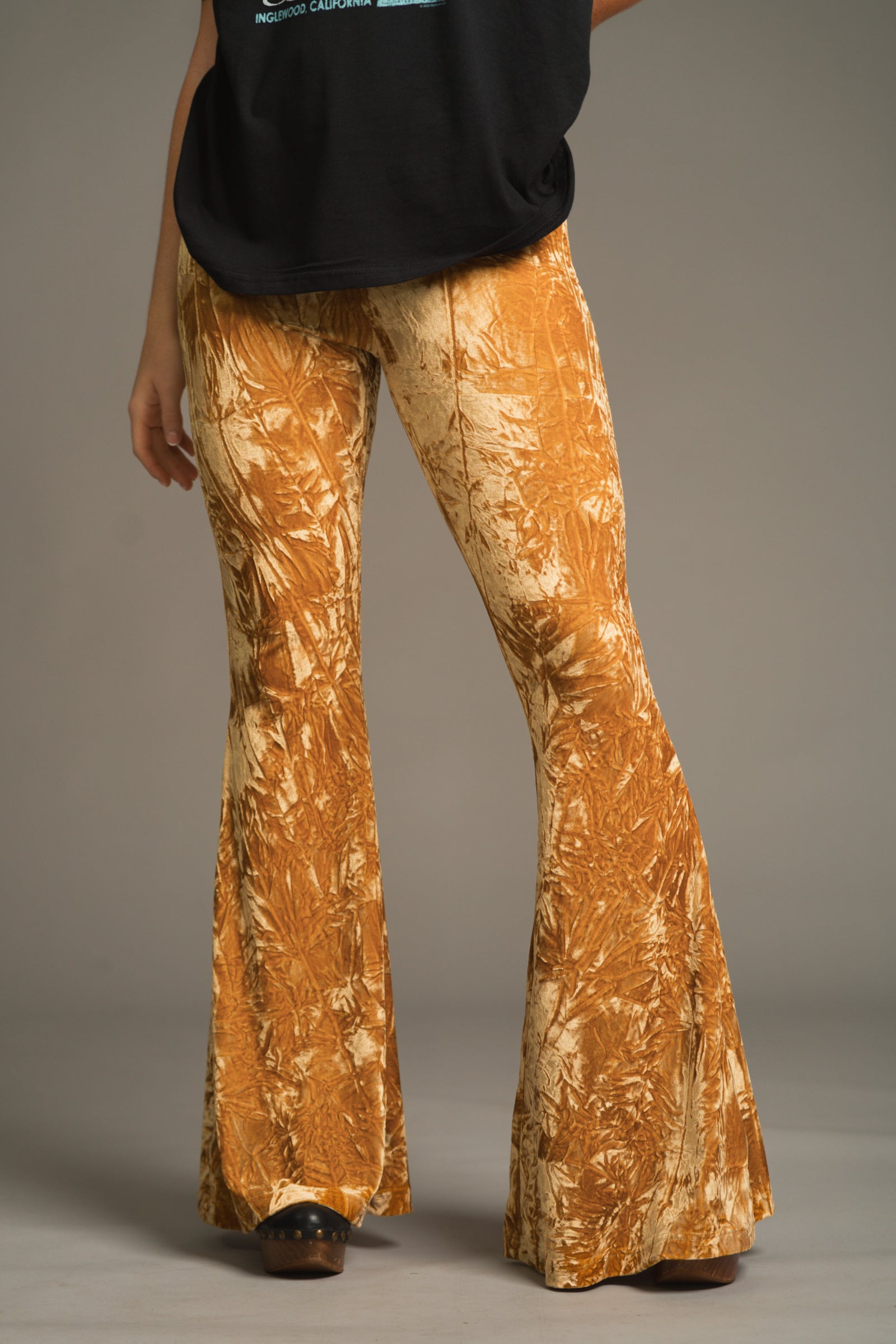 Front view of model wearing Hendrix Ochre crushed velvet flared pants, 70s inspired Flares
