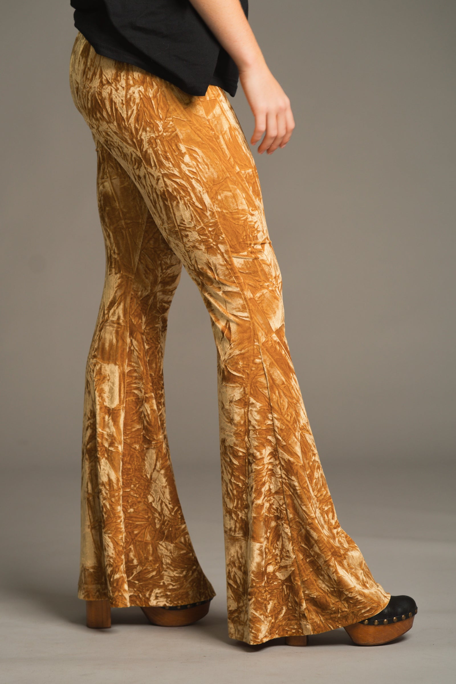 Side profile of Hendrix velvet flares showing high-rise fit and golden crushed texture