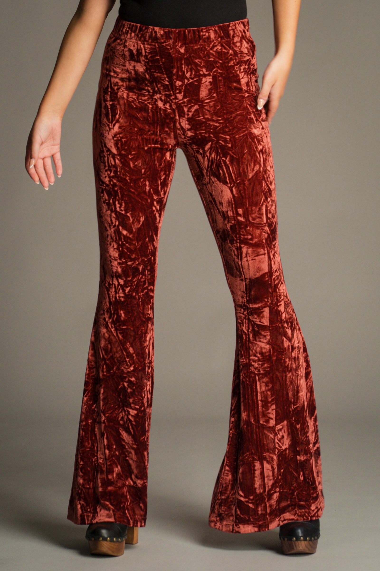 Close-up front view of Hendrix Rust Crushed Velvet Flares featuring a high-rise fit, soft stretch velvet fabric and dramatic flared leg