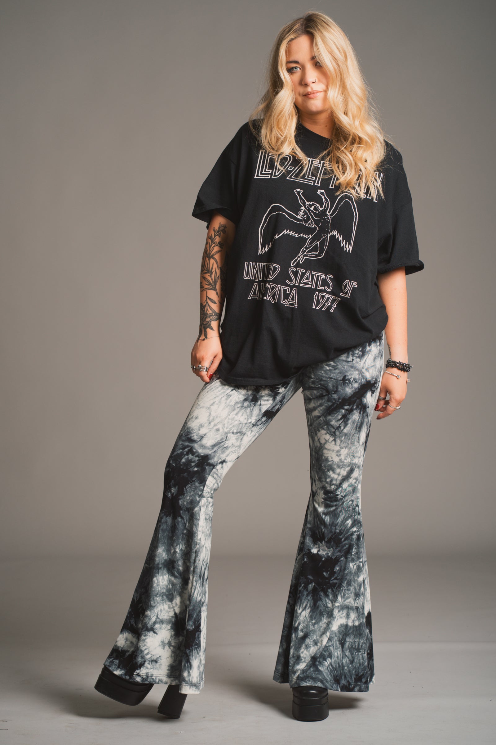 Erin models Little Lies Hendrix tie dye flared trousers styled with oversized black Led Zeppelin band tee in studio setting
