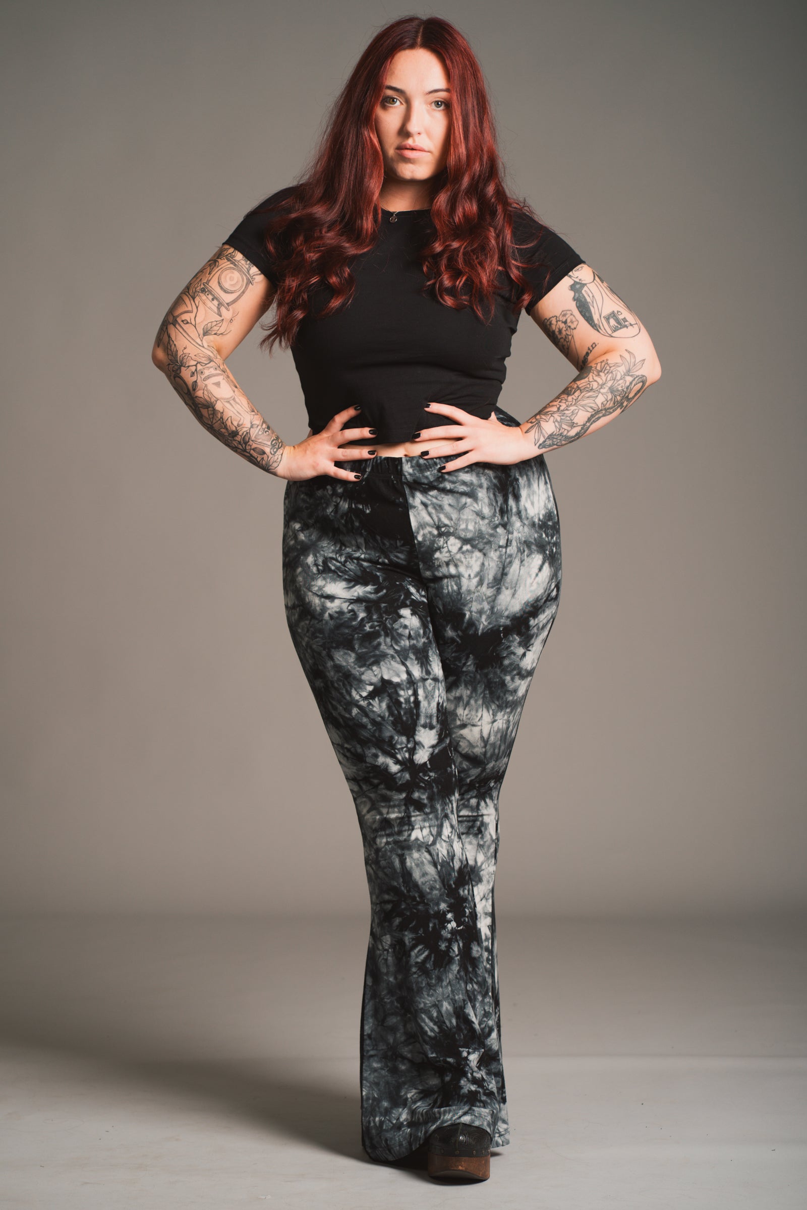 Taylor models Little Lies Hendrix tie dye flared trousers in black and grey styled with fitted black tee, front view studio shot