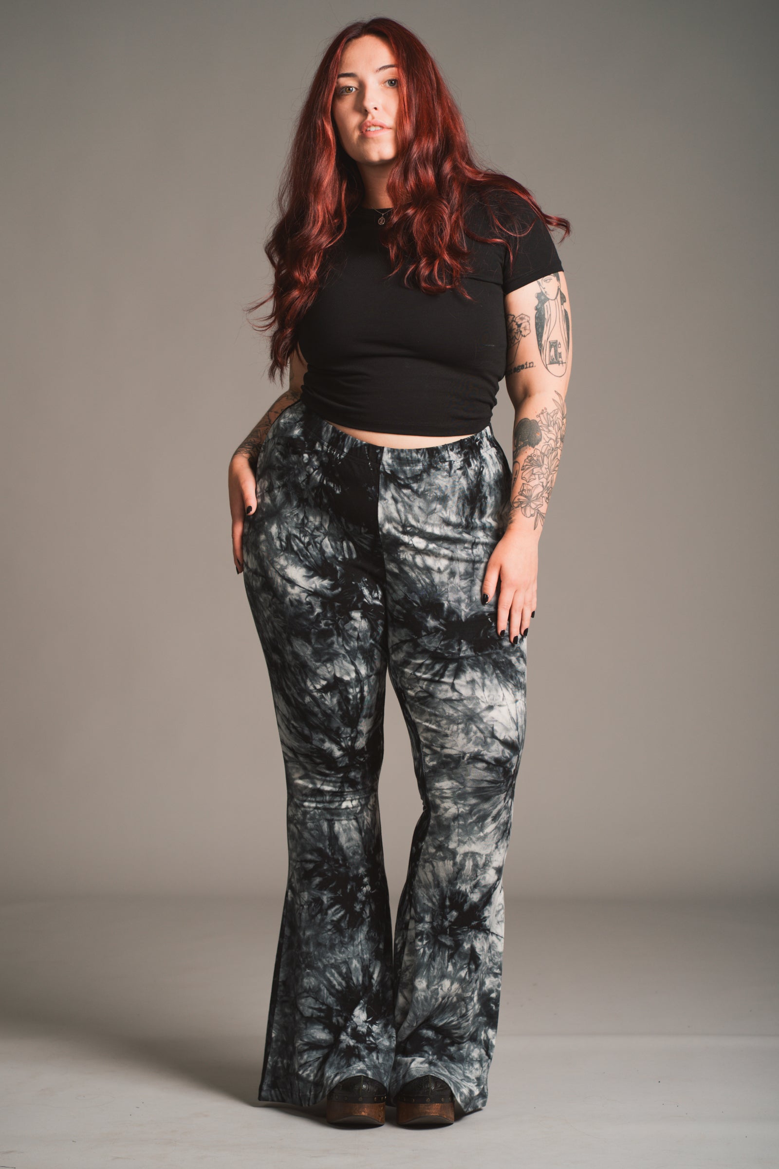 Taylor models Little Lies Hendrix tie dye flared trousers in black and grey styled with fitted black tee, front view studio shot