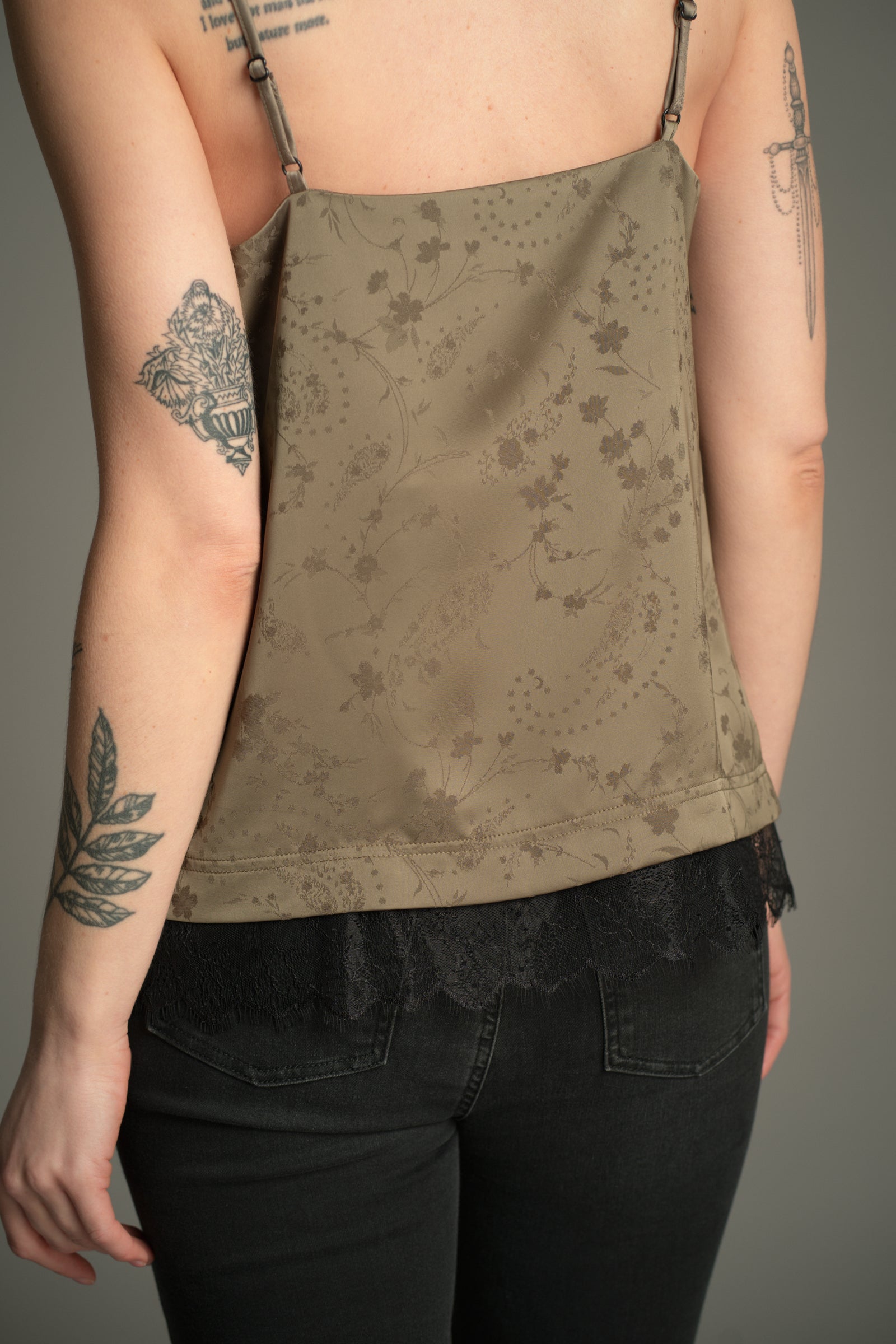 Back view of the Little Lies Iris Satin Cami in sage satin with tonal floral jacquard and black lace trim, styled with denim flares.