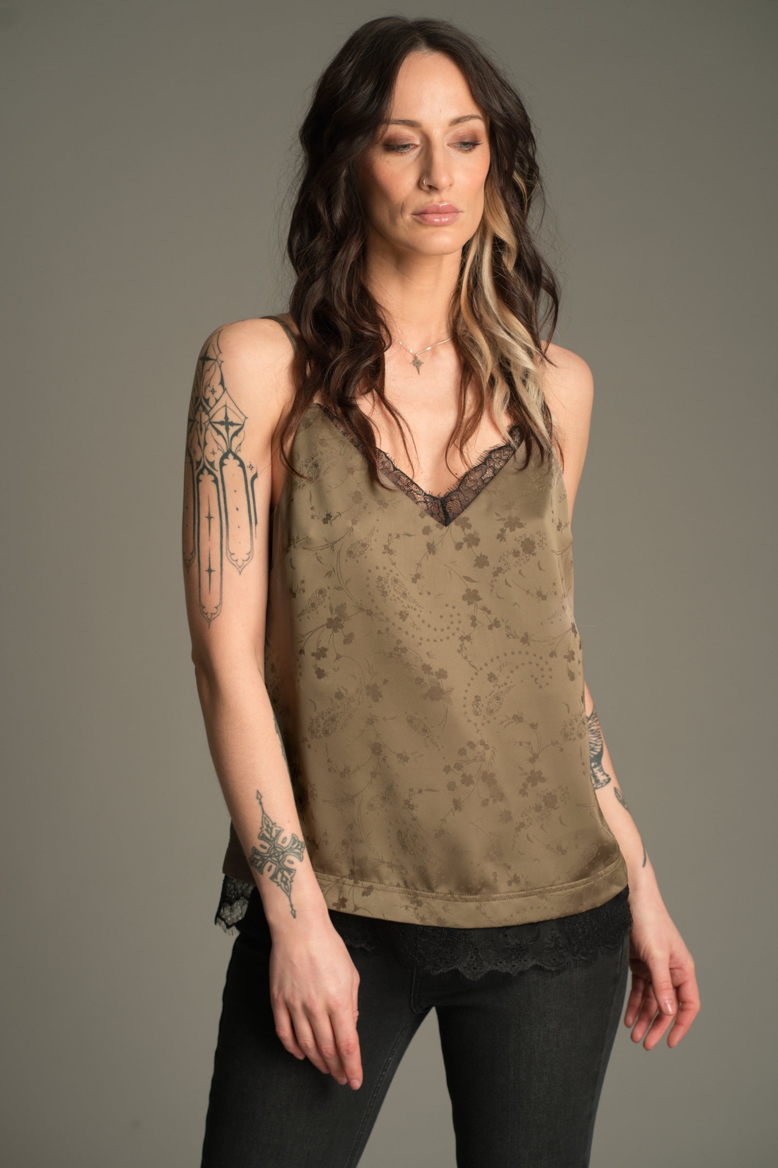 Front view of Victoria wearing the Little Lies Iris Satin Cami in sage satin with tonal floral jacquard and black lace trim, styled with black jeans.