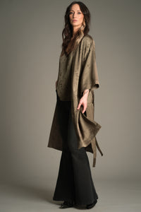 Side view of Victoria wearing the Little Lies Iris Satin Kimono in olive satin with a subtle floral jacquard pattern, layered over a matching Iris Satin cami and styled with denim flared trousers.