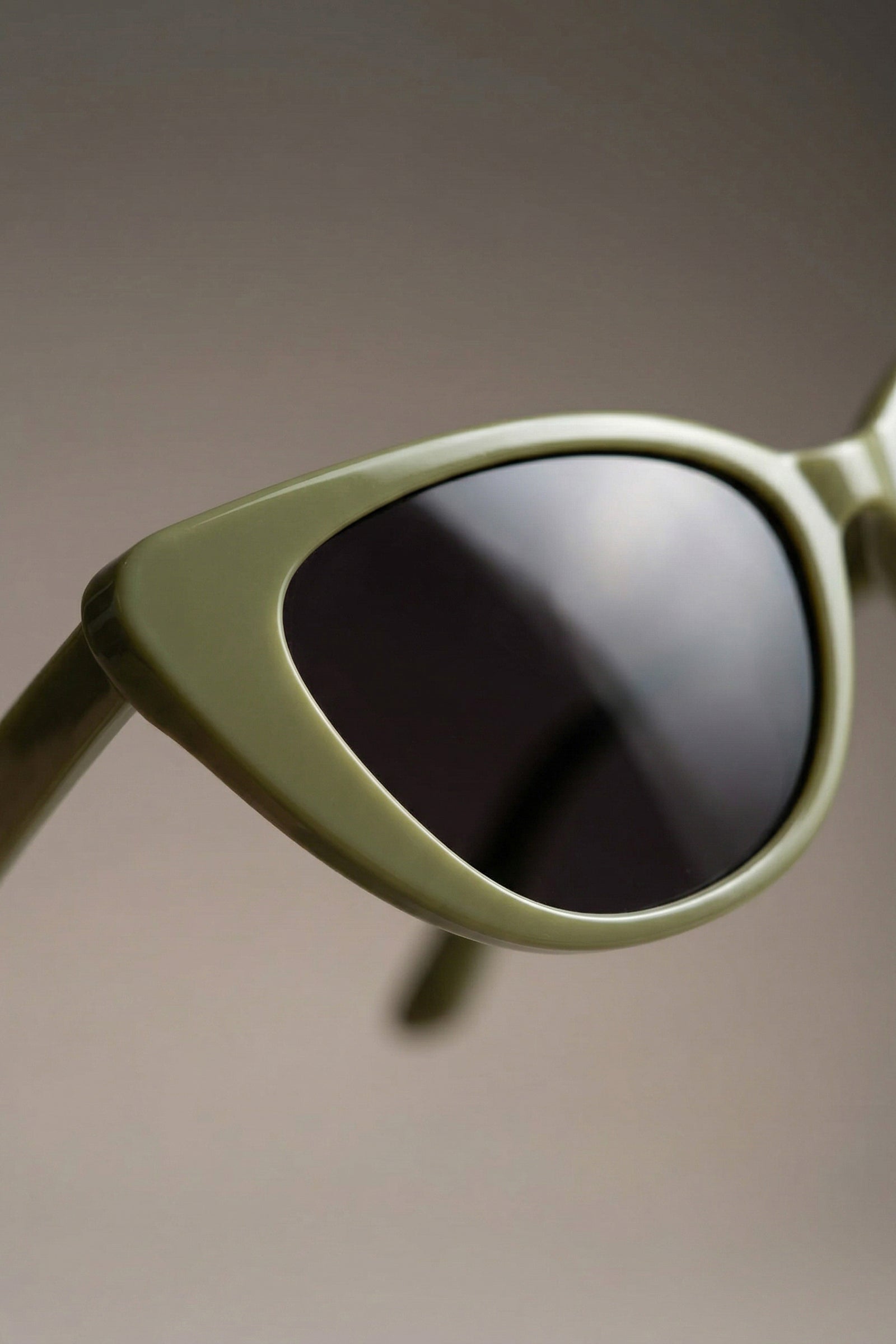 Close-up side detail of olive cat eye sunglasses with dark lenses