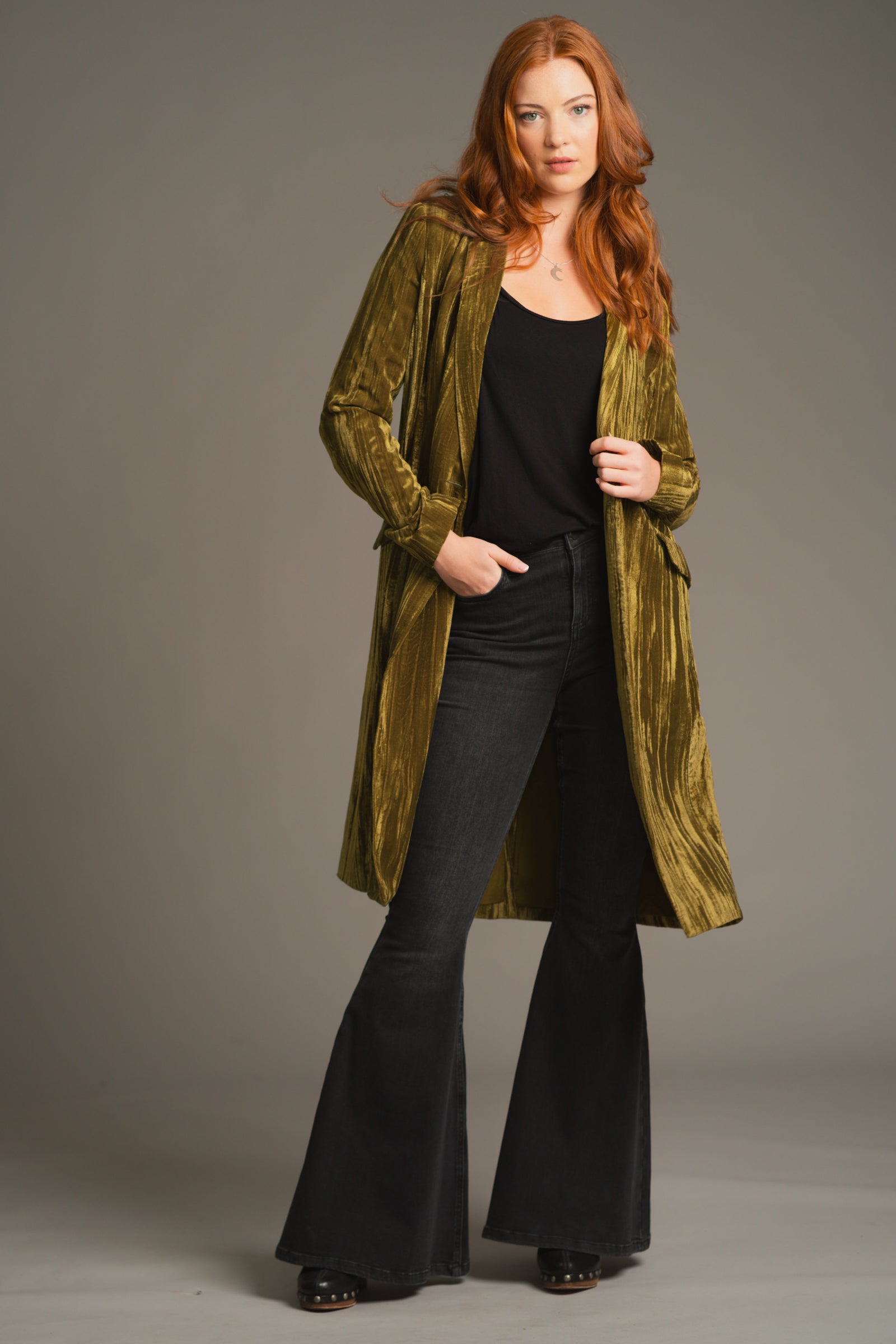 Front view of Anna wearing Jagger Olive crushed velvet duster jacket with black flared trouser