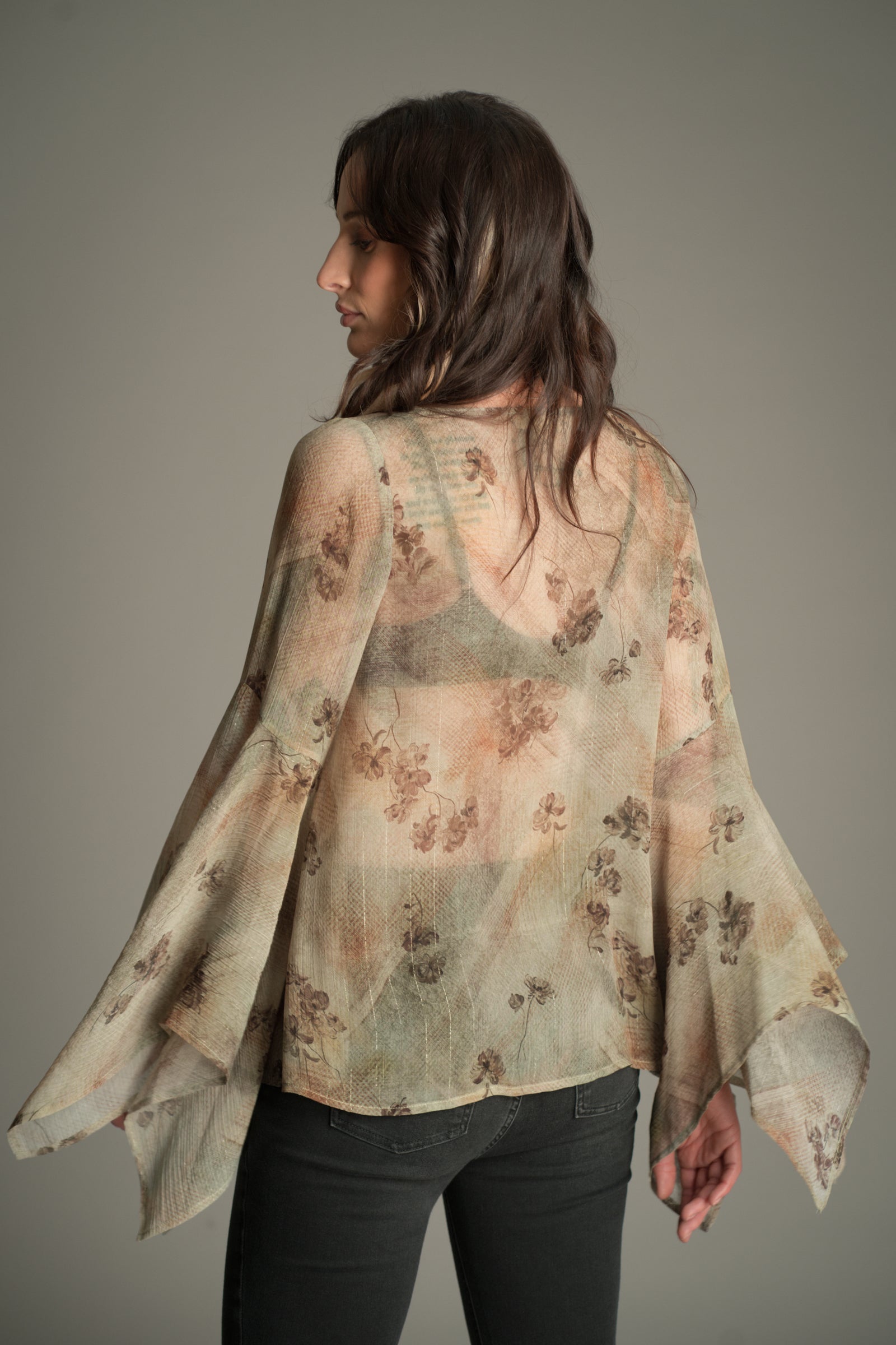 Back view of the Little Lies Karma Sage Blouse in soft sage tones with floral print, featuring flared sleeves and a lightweight semi‑sheer finish.