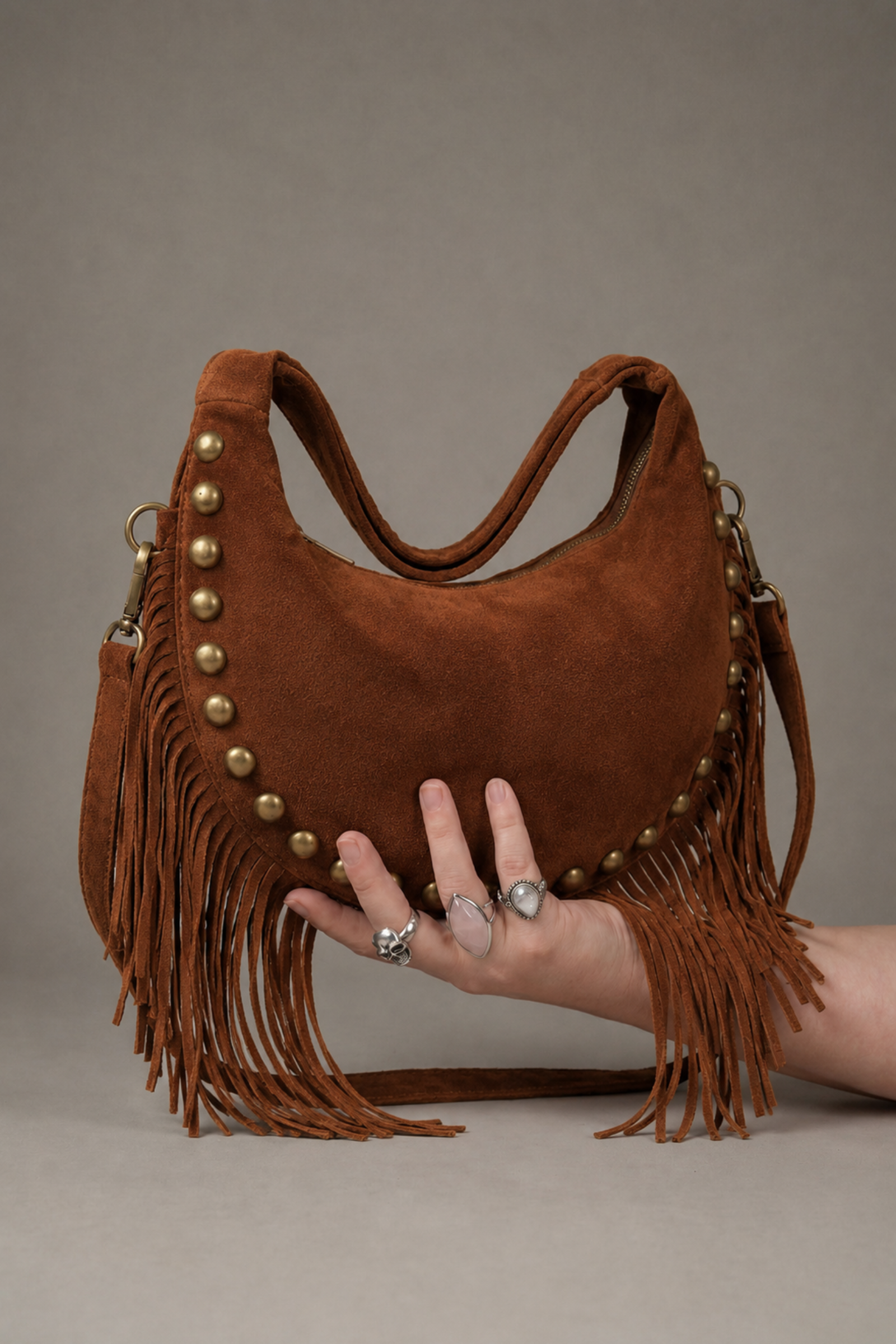 Little Lies Kate tan suede studded fringe bag – relaxed shoulder bag front held by model
