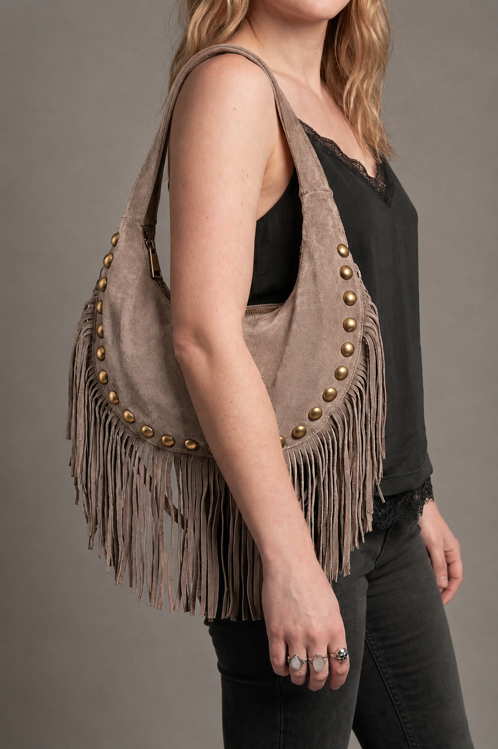 Little Lies Kate taupe genuine suede studded fringe bag, slouchy hobo style with tassel trim, on‑body side view