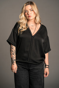 Model wears Little Lies Lita Studded Satin Tee front view showing deep V-neckline and velvet-backed stud trim