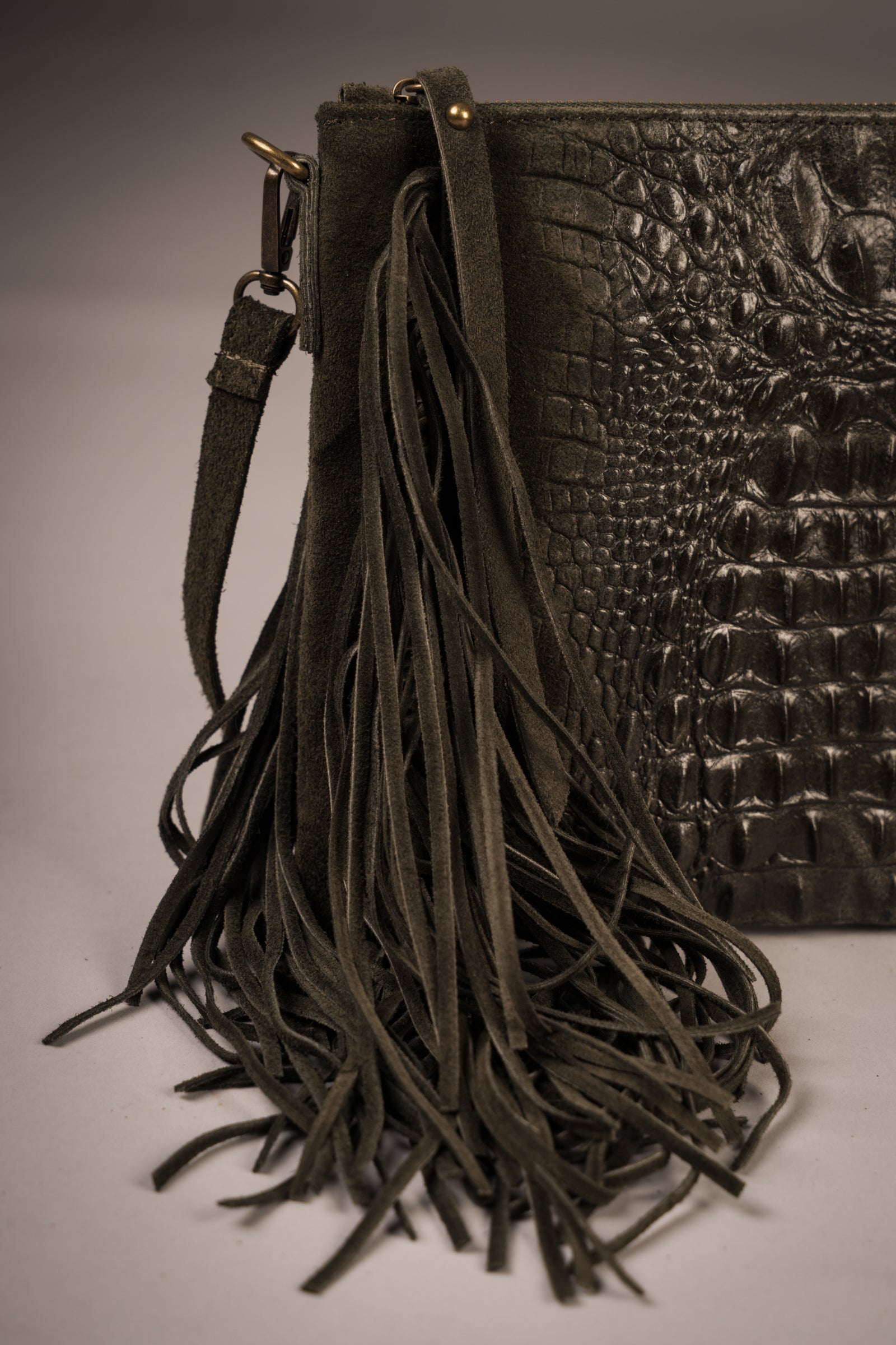 Close-up of Little Lies Niska Khaki Genuine Suede Fringed Bag with crocodile-embossed texture and long suede fringe detail, studio setting