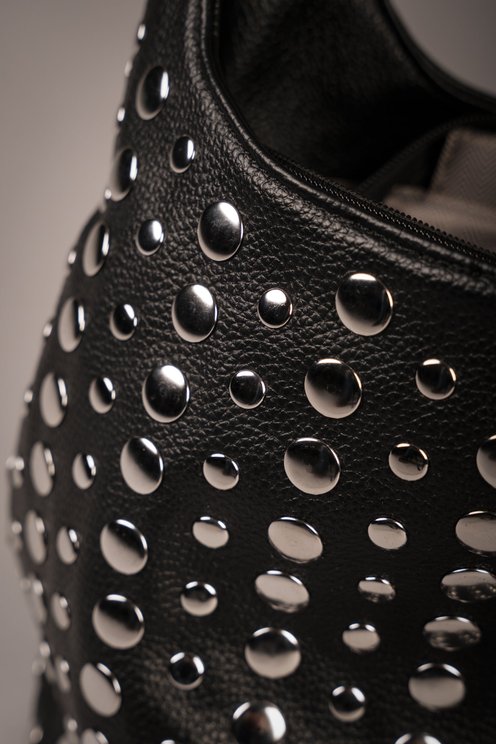 Close-up of Little Lies Viva black leather handbag featuring silver-tone stud hardware and textured finish, studio setting.
