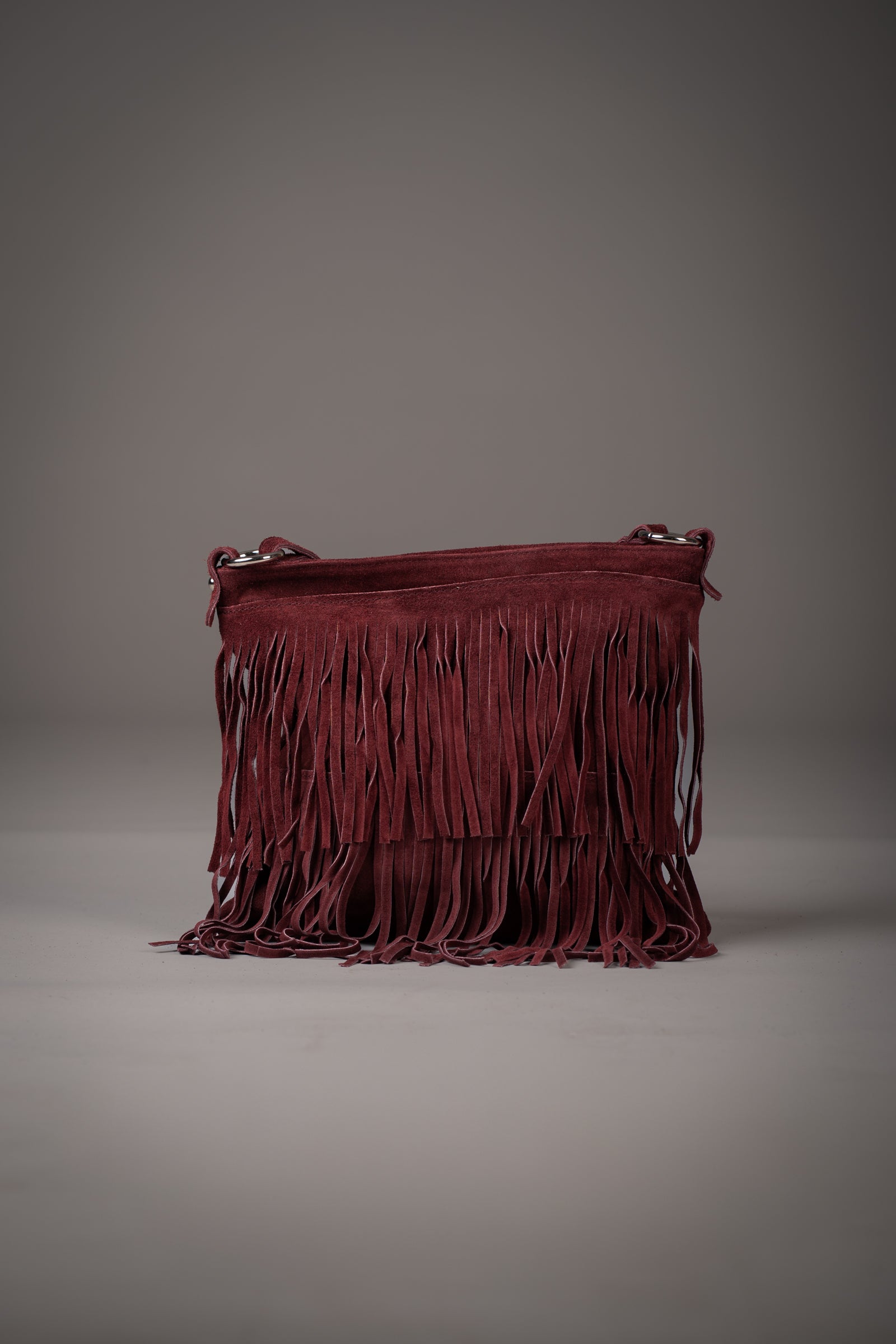 Little Lies Oxblood Genuine Suede fringed shoulder bag with long tassel detailing, photographed in a studio setting
