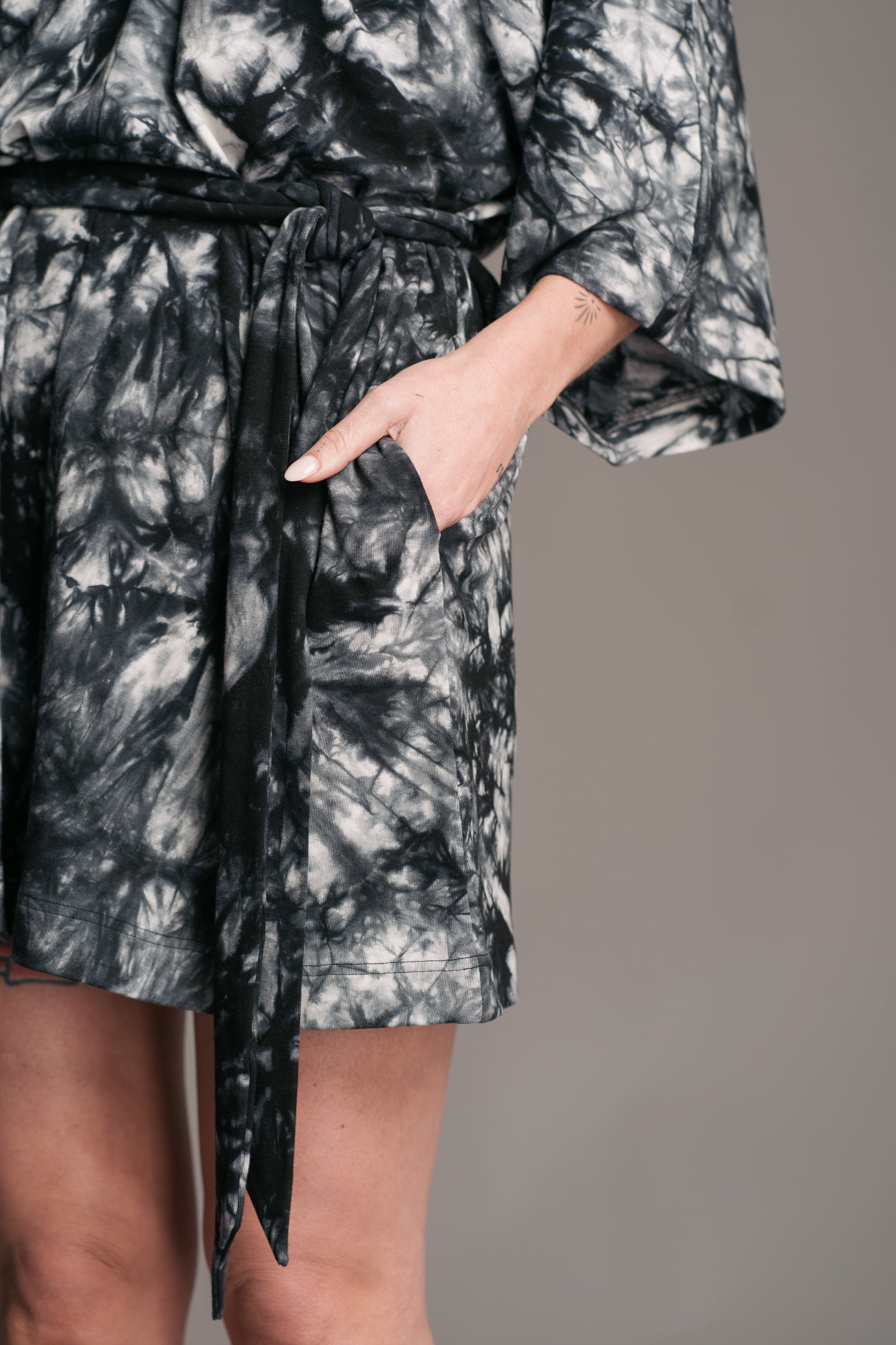 Joplin Tie Dye Mini Dress worn onset by brunette model, Bex, also wearing black leather wooden clogs. Detail shot showing the matching tie dye waist tie which doubles as a skinny scarf