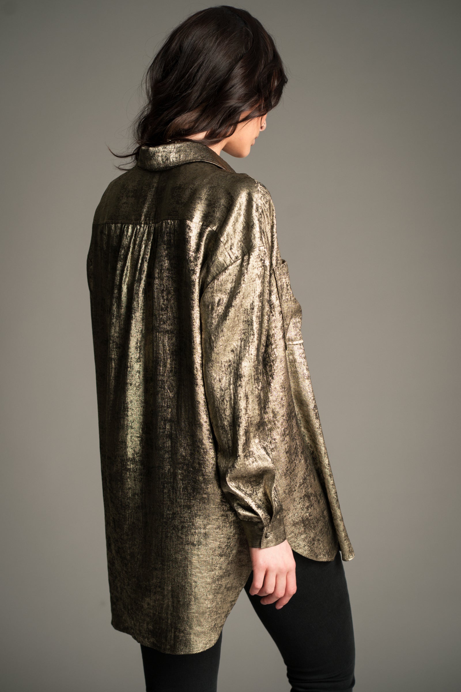 Victoria wears Little Lies Luna Metallic Shirt in gold, back view showing relaxed longline fit.