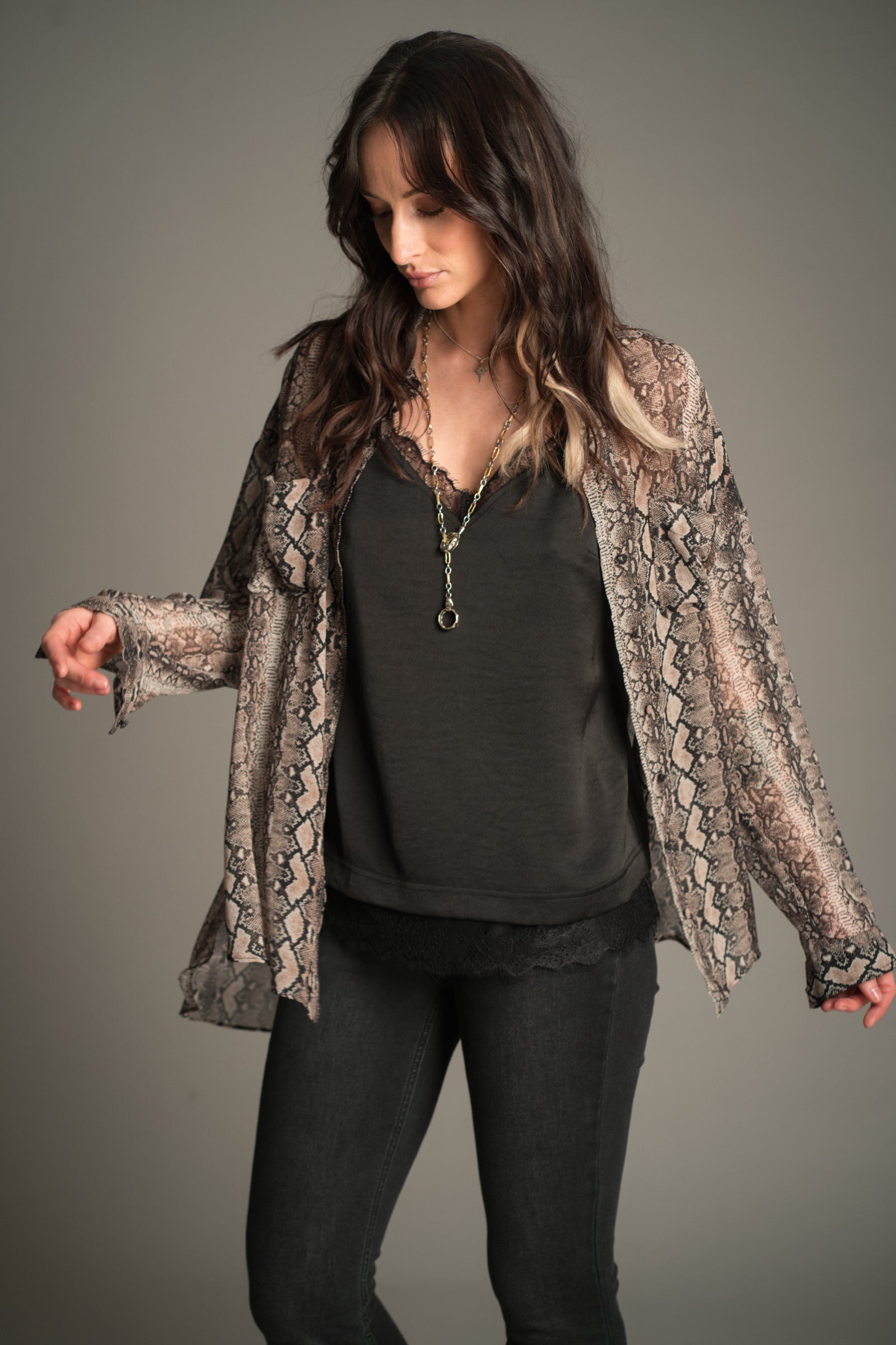 Victoria wears Little Lies Mosshart Snake Chiffon Shirt in sheer snake print, front angle showing lightweight longline fit worn open over a black satin cami and skinny jeans.