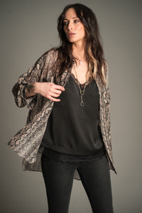 Victoria wears Little Lies Mosshart Snake Chiffon Shirt in sheer snake print, front angle showing lightweight longline fit worn open over a black satin cami and skinny jeans.