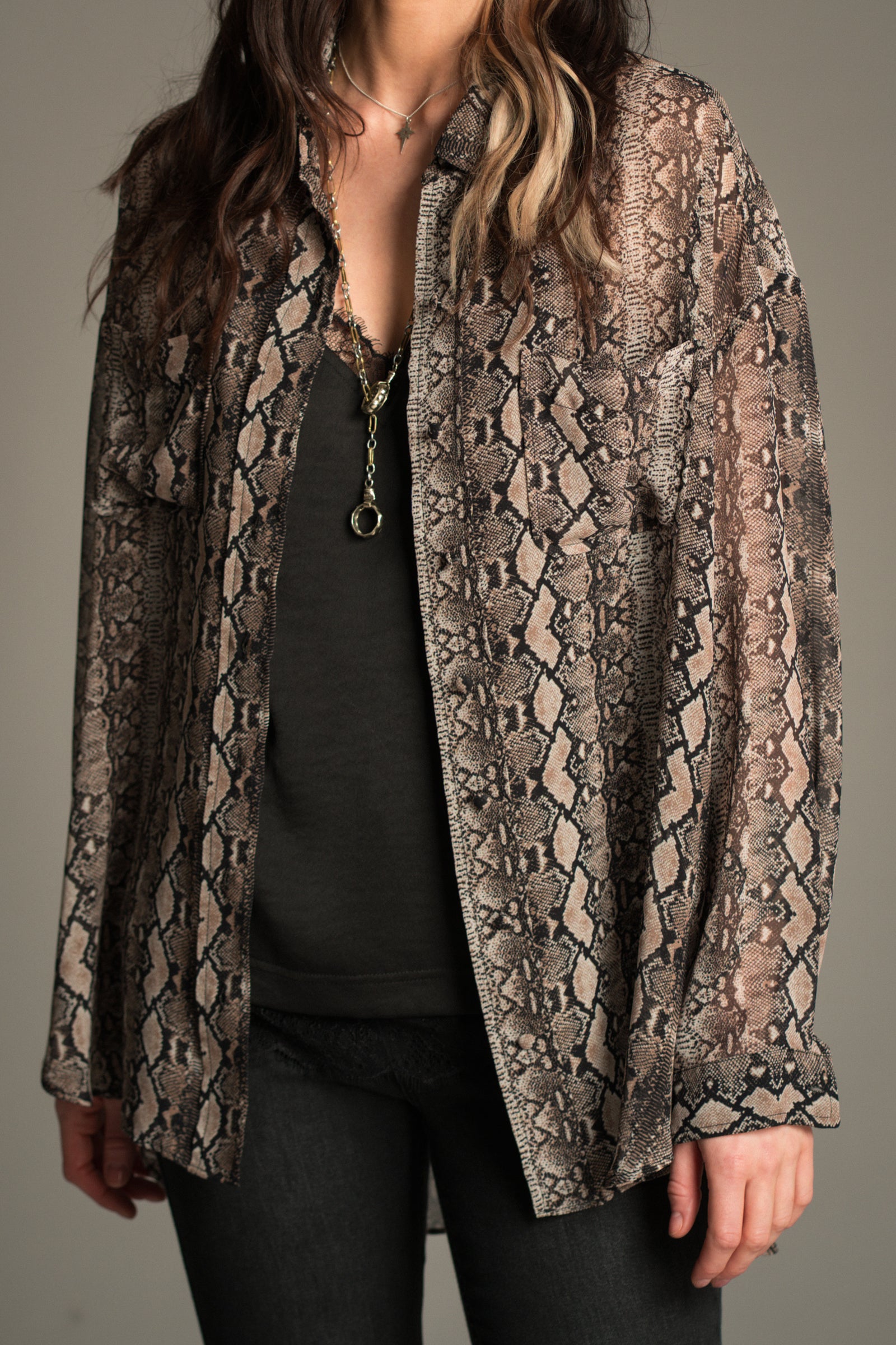 Close up of Little Lies Mosshart Snake Chiffon Shirt in sheer snake print, front view showing lightweight longline fit styled open over a black satin cami.