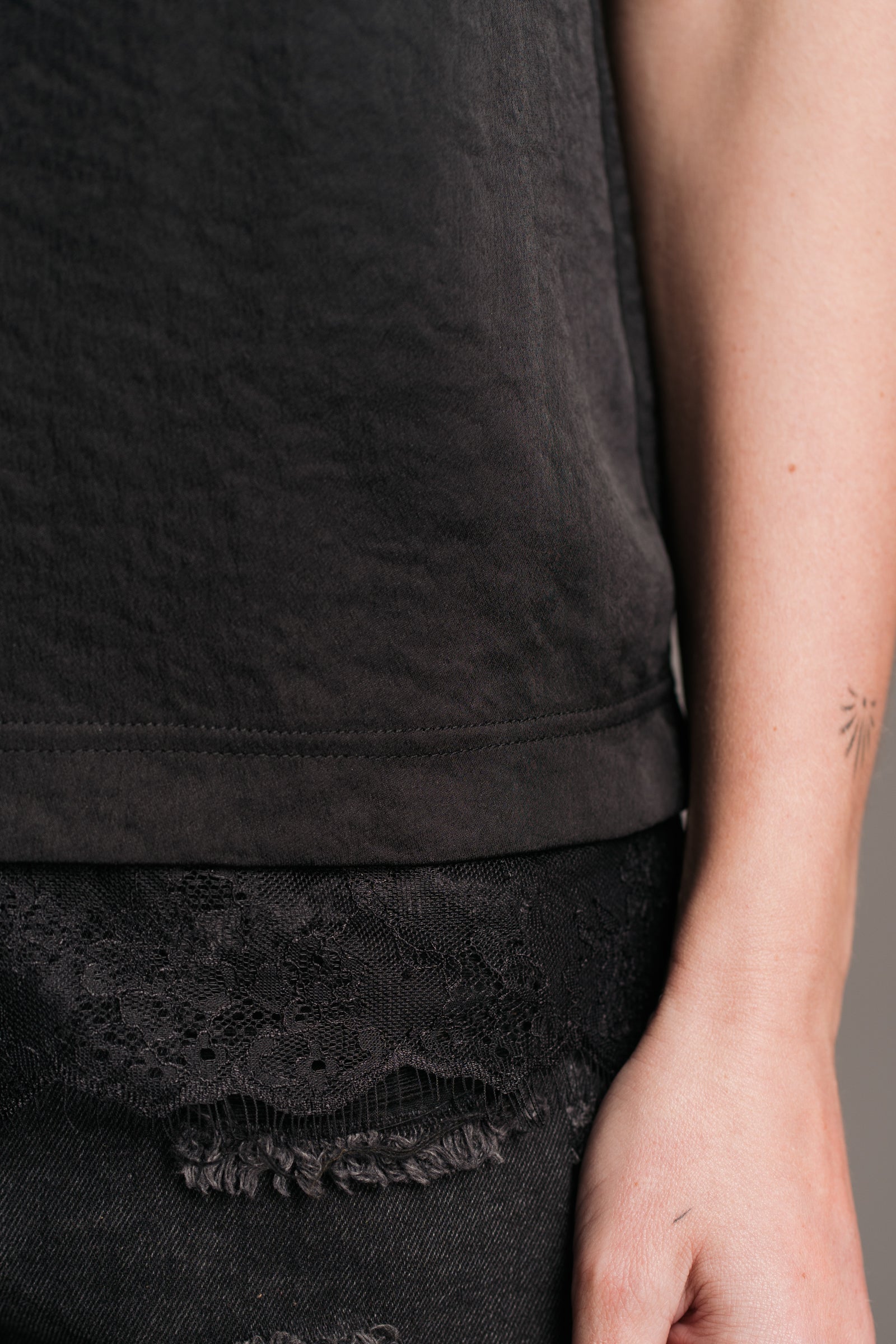 Little Lies Nightbird black cami top with delicate lace trim detail – close-up view paired with distressed black denim