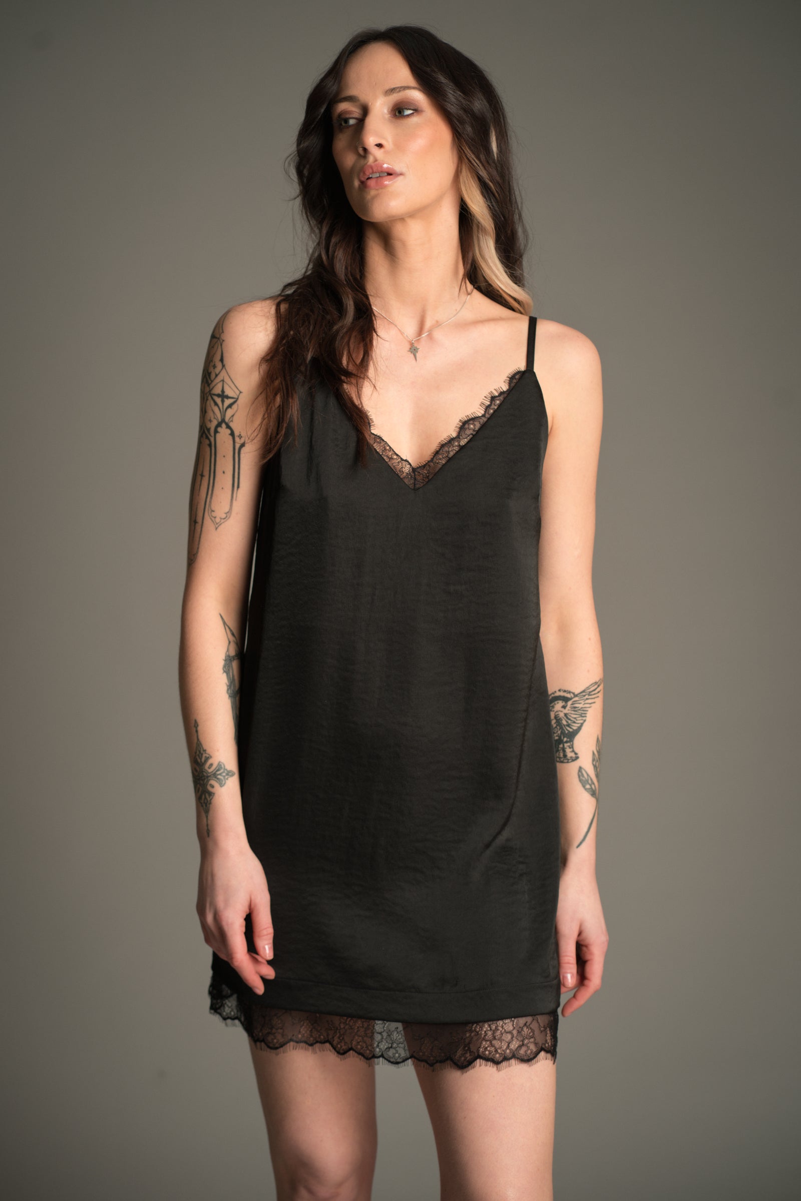 Victoria wears Little Lies Nightbird Satin Slip Dress in black, front view showing lace‑trim neckline and hem.
