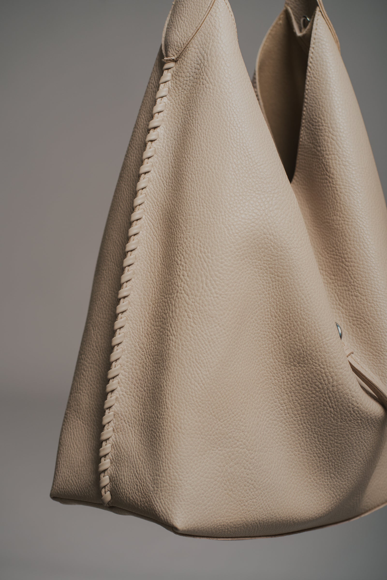 Sadie Taupe Faux Leather Hobo handbag held by a model against a neutral background