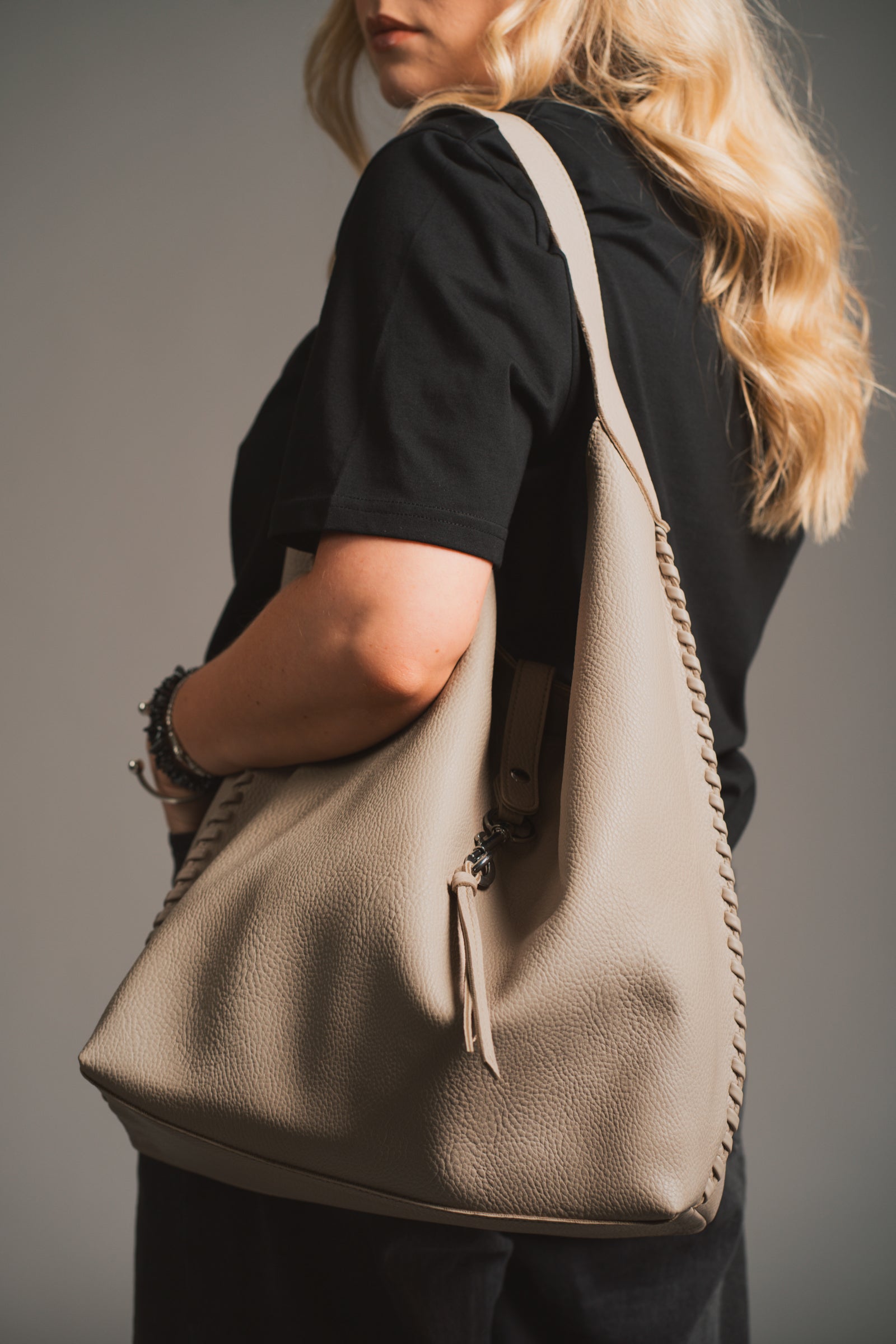 Sadie Taupe Faux Leather Hobo handbag held by a model against a neutral background